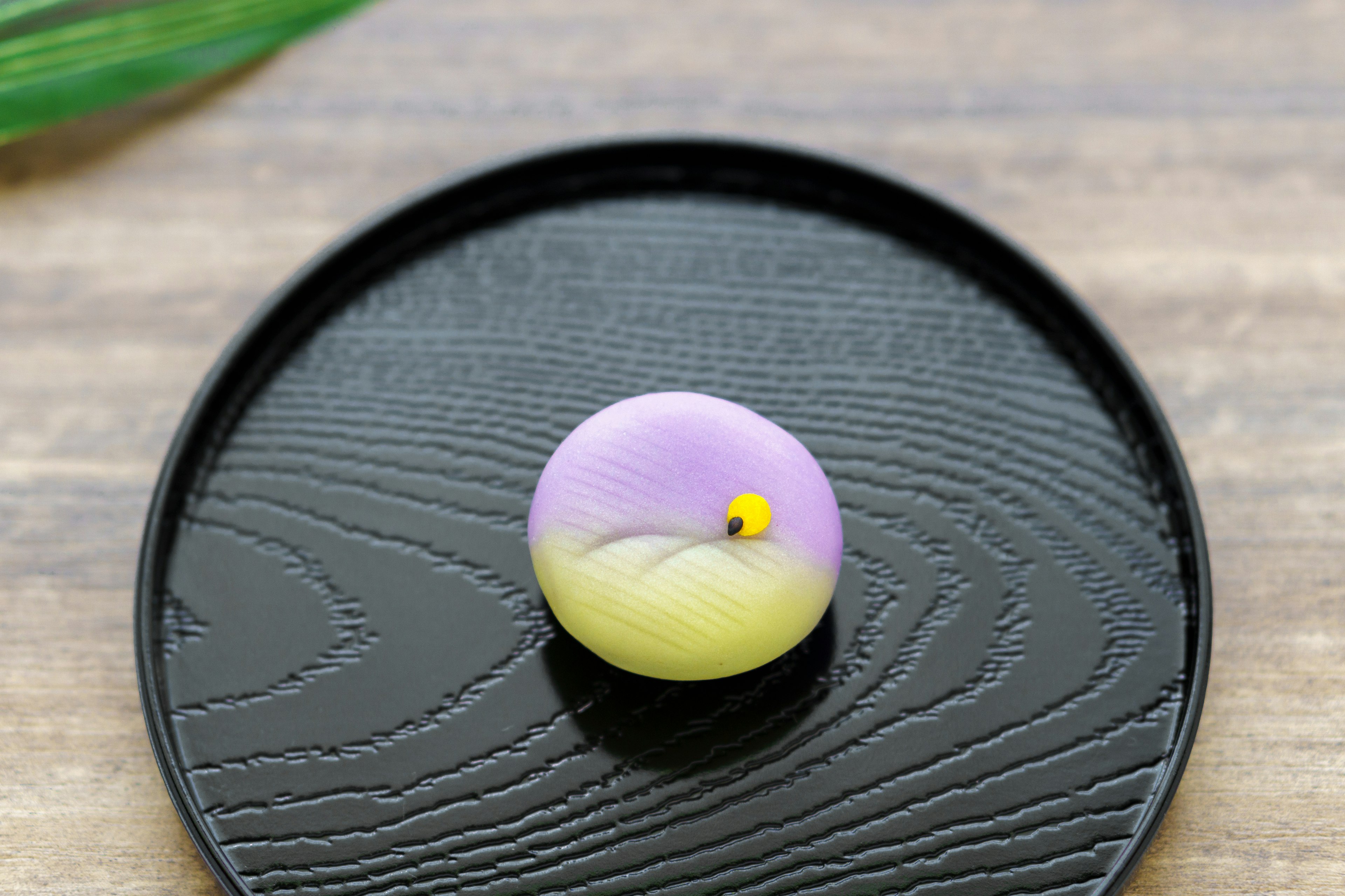 Une belle confiserie japonaise violette et jaune sur une assiette noire