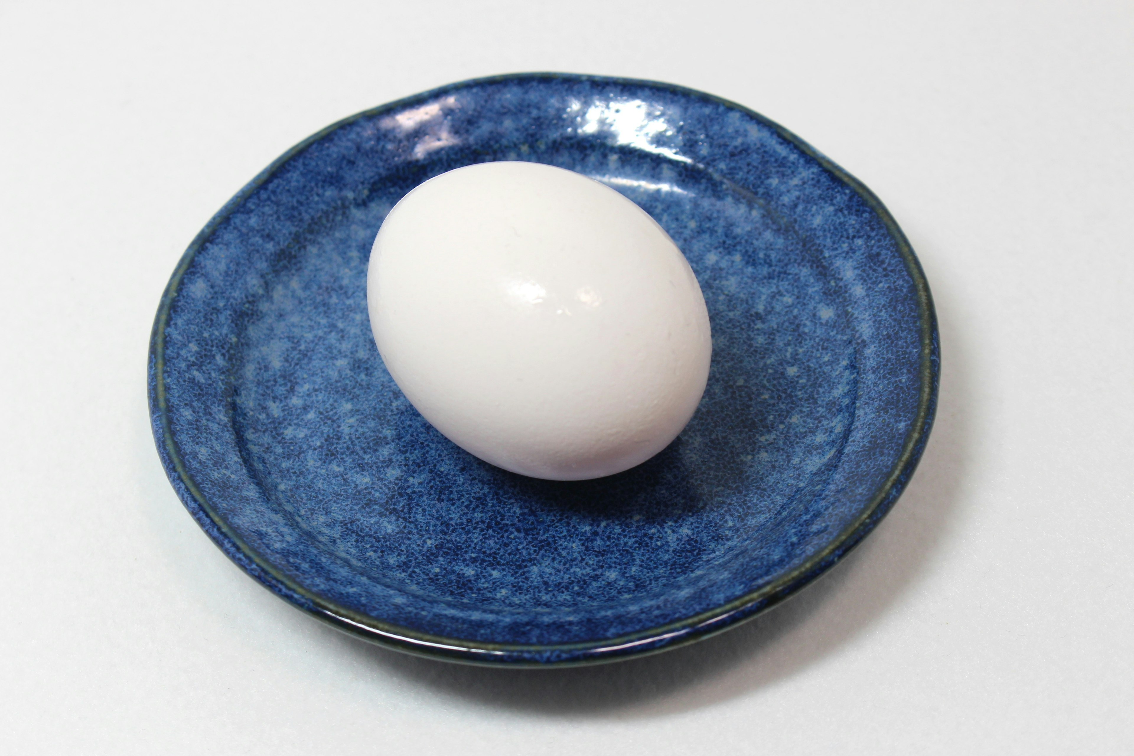 A white egg placed on a blue plate