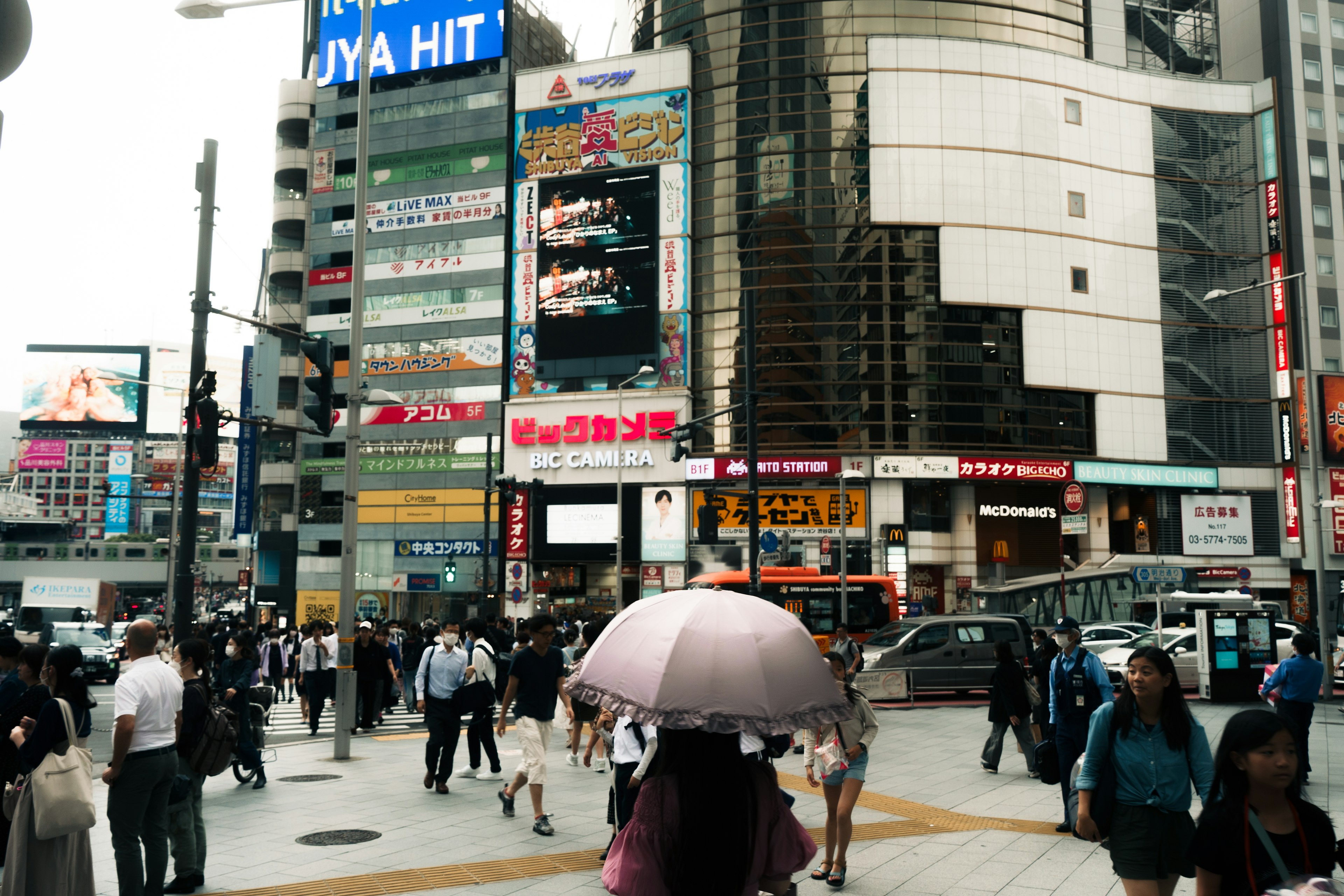 渋谷の繁華街で傘を持った人々が行き交う様子