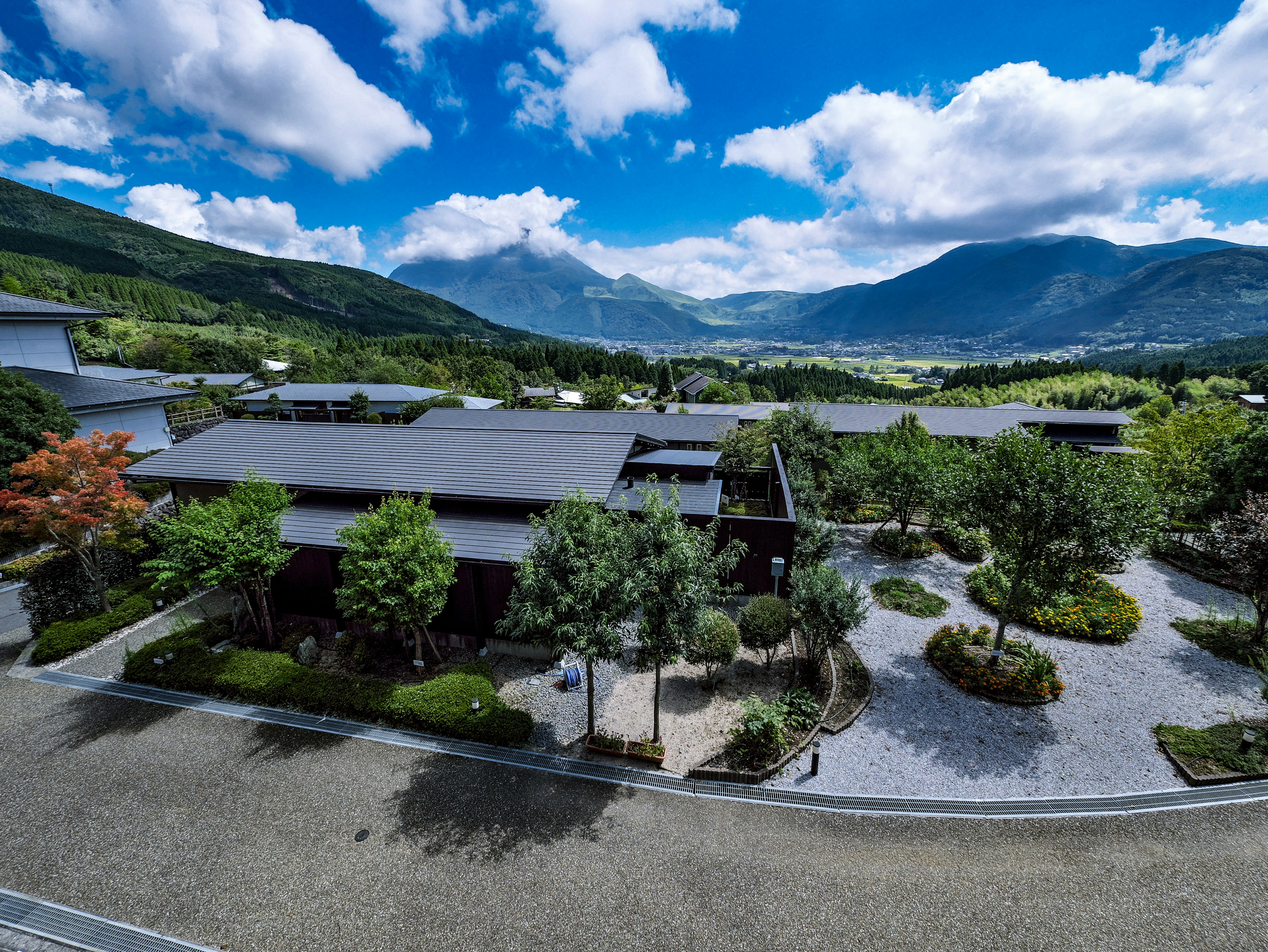 Modern building with landscaped gardens set against a backdrop of mountains and blue sky