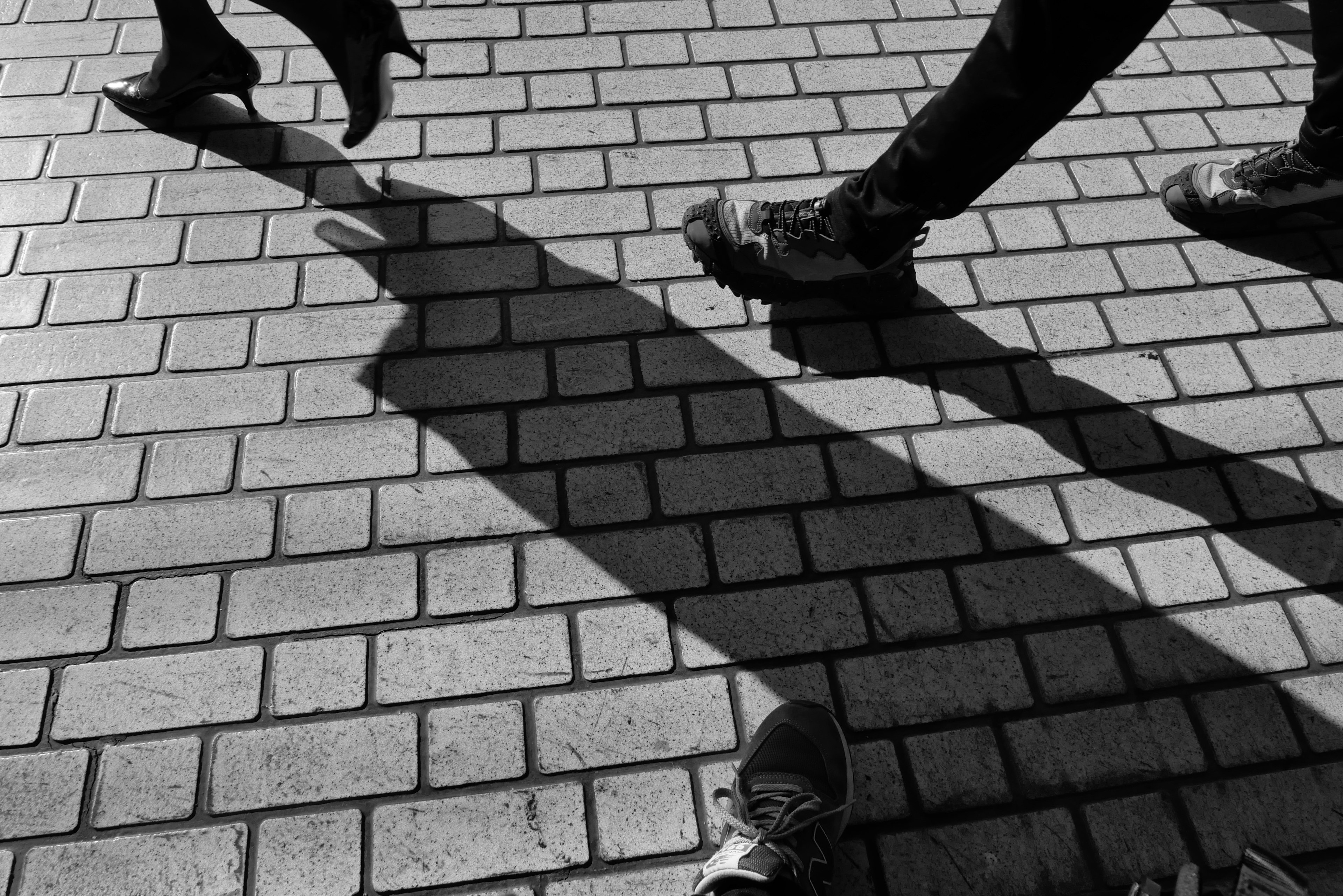 Black and white street scene showing the shadows of walking people