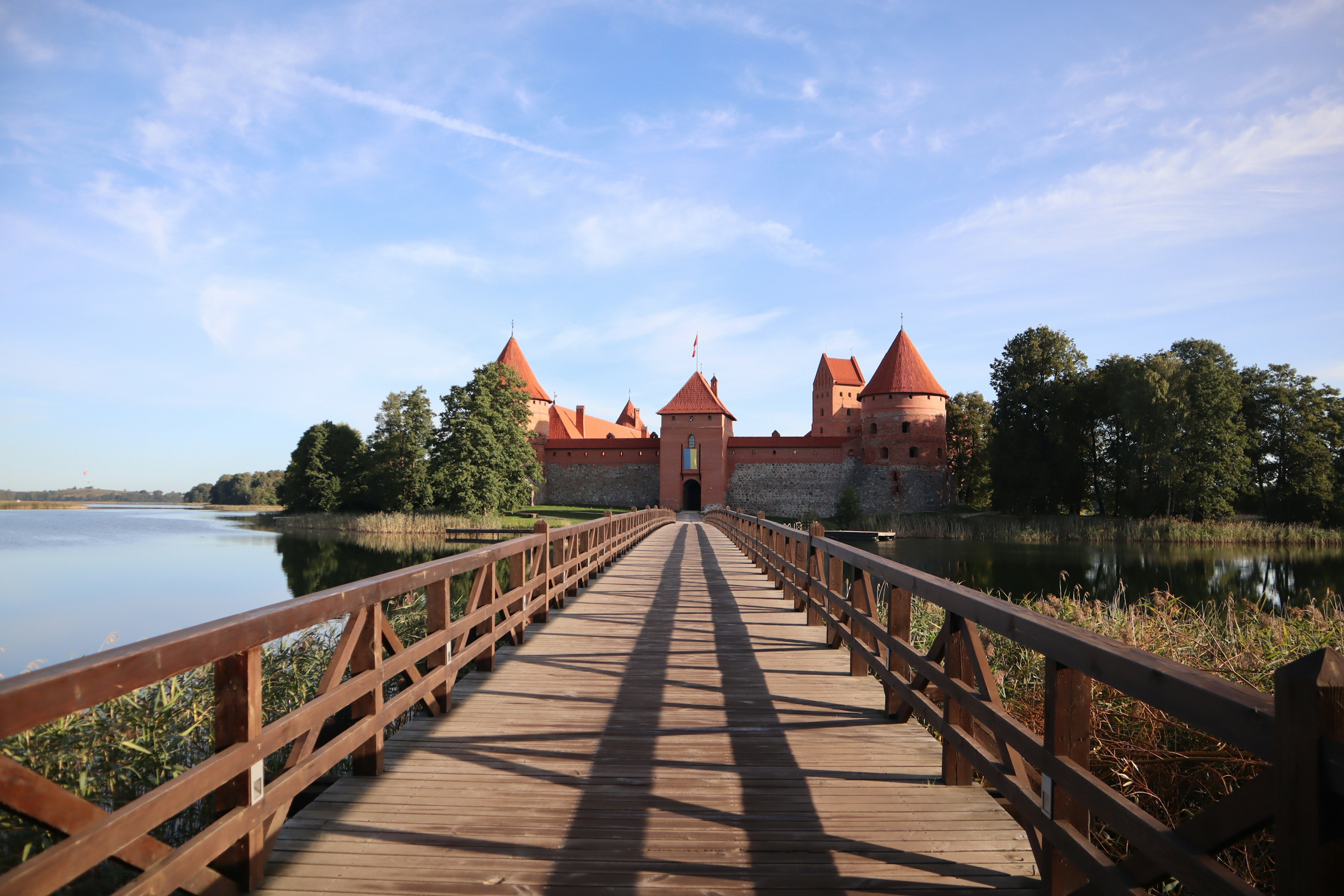 Puente de madera que conduce al castillo de Trakai con un lago sereno de fondo