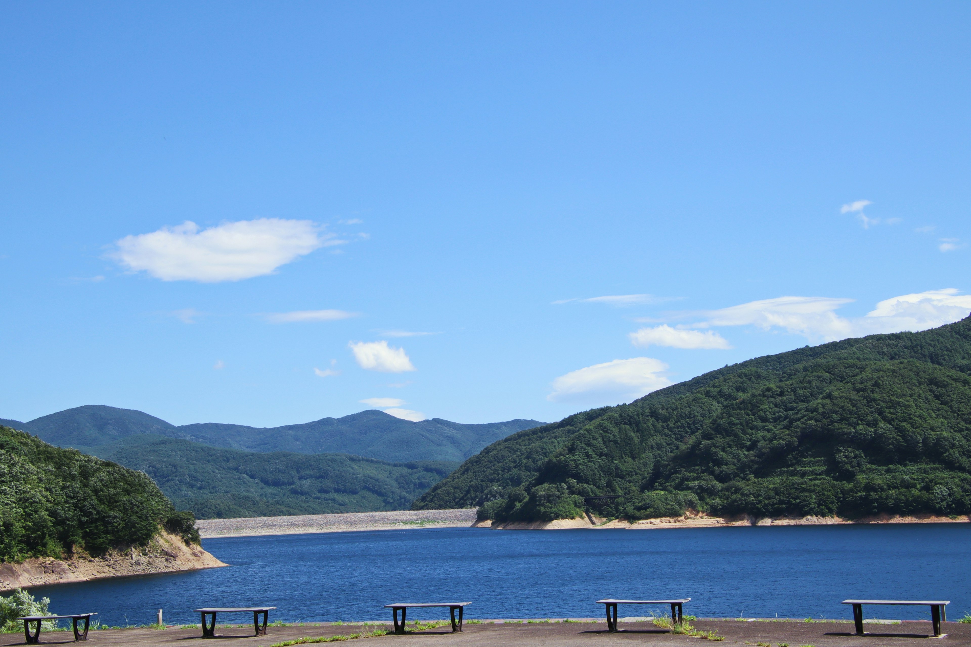 宁静的湖泊风景，四周环绕着绿色的山脉和蓝天