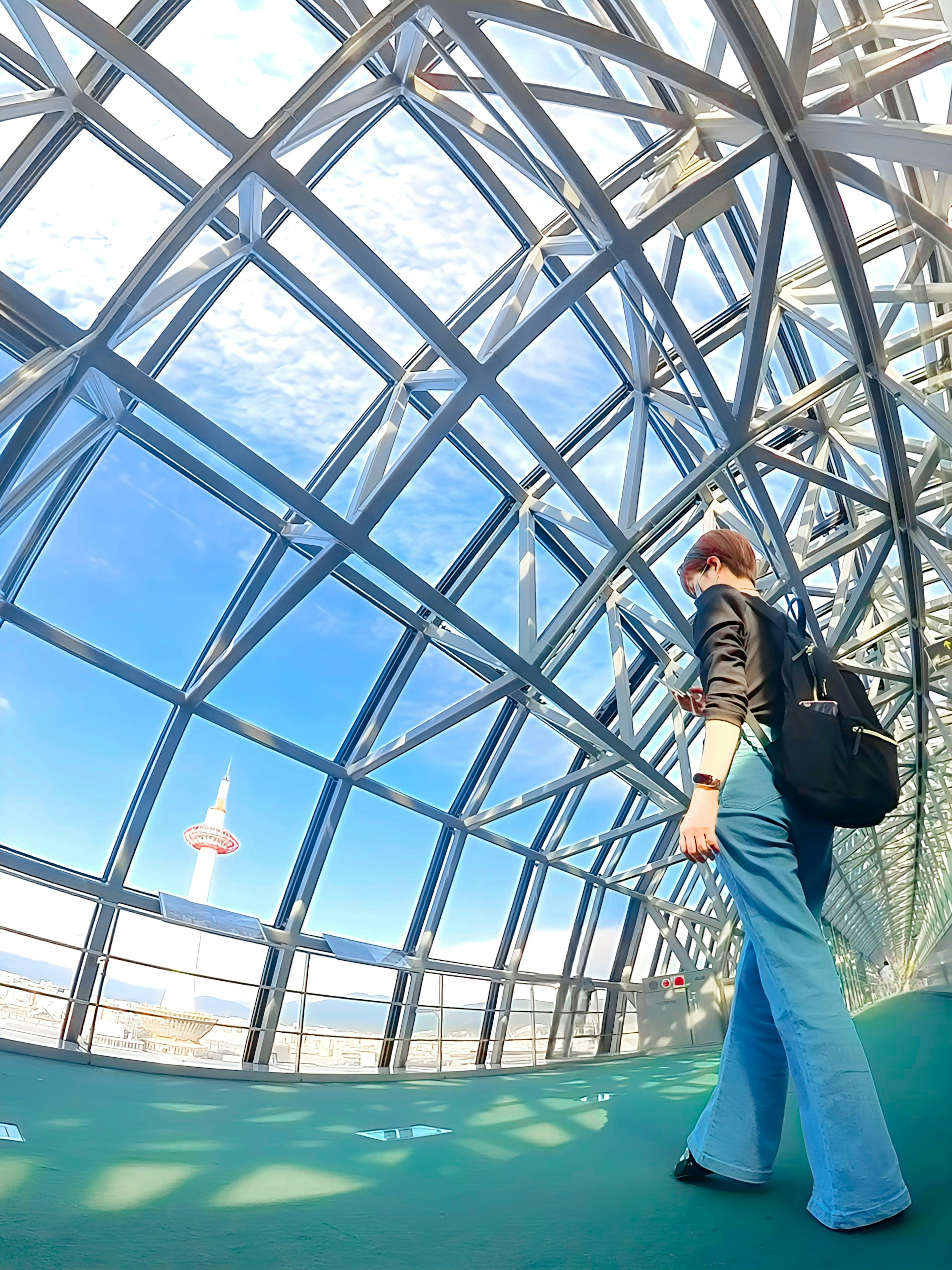 Woman walking inside a glass structure with blue sky