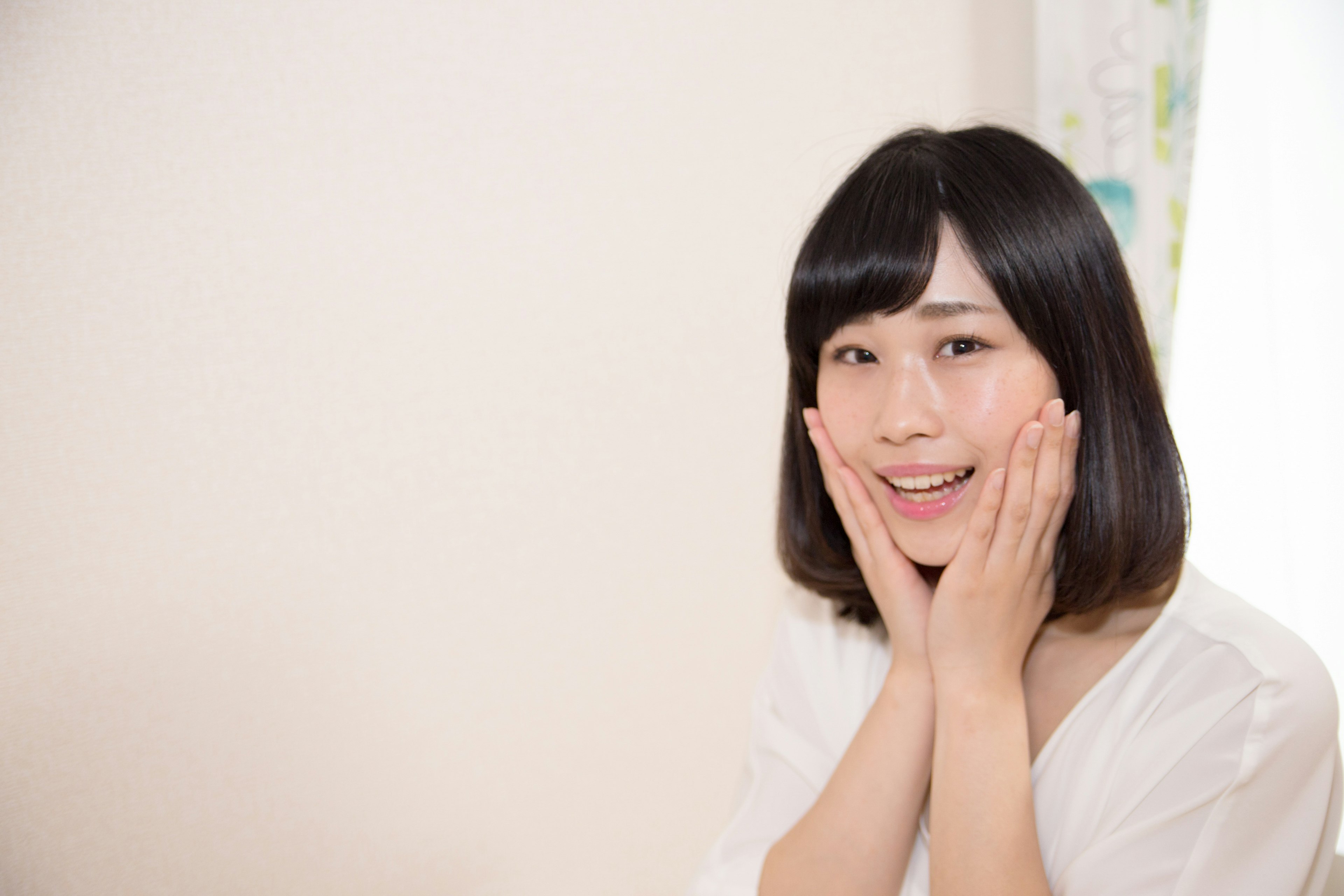 A woman in a white top smiling with a surprised expression