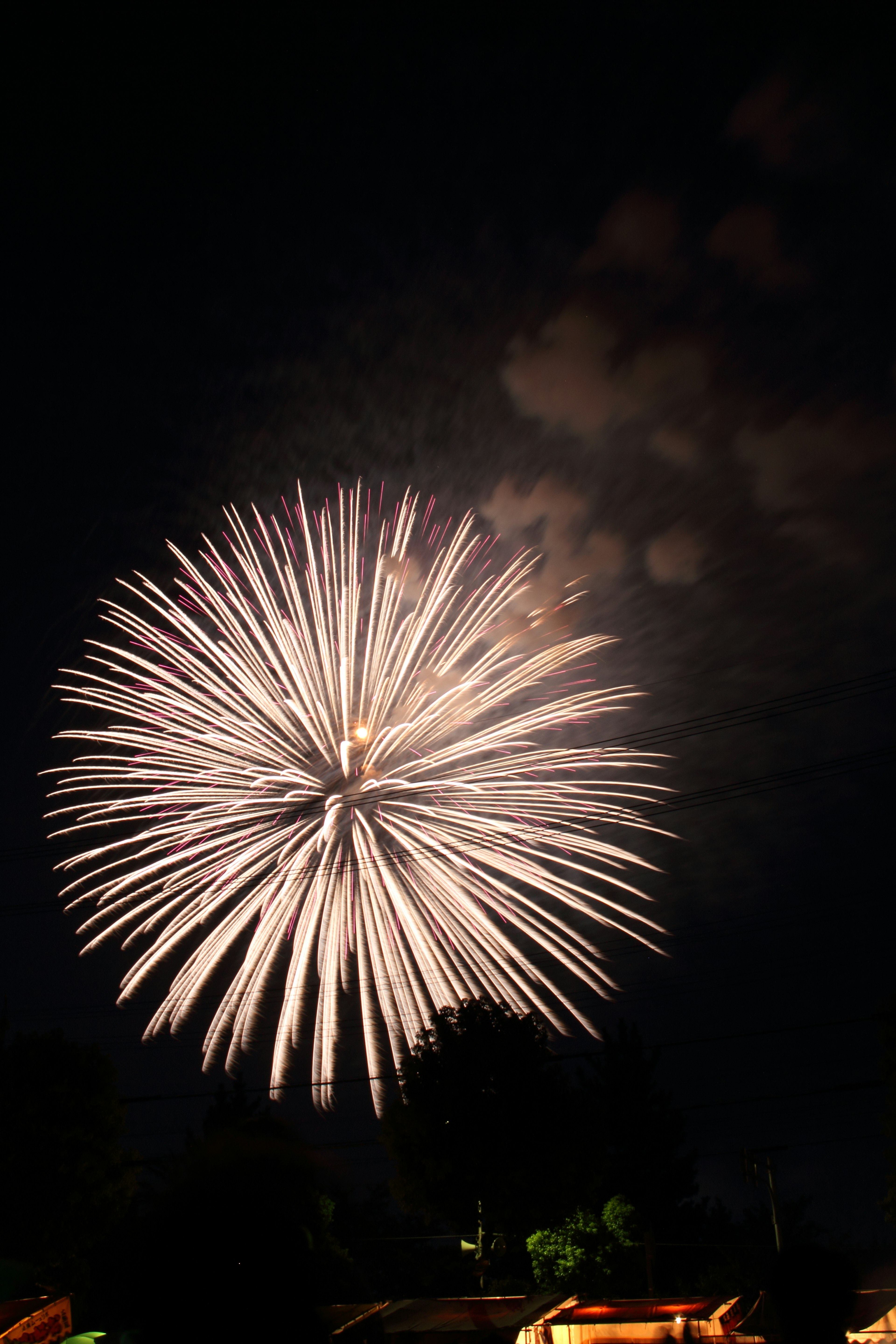 Großes Feuerwerk, das im Nachthimmel mit weißen und gelben Funken explodiert