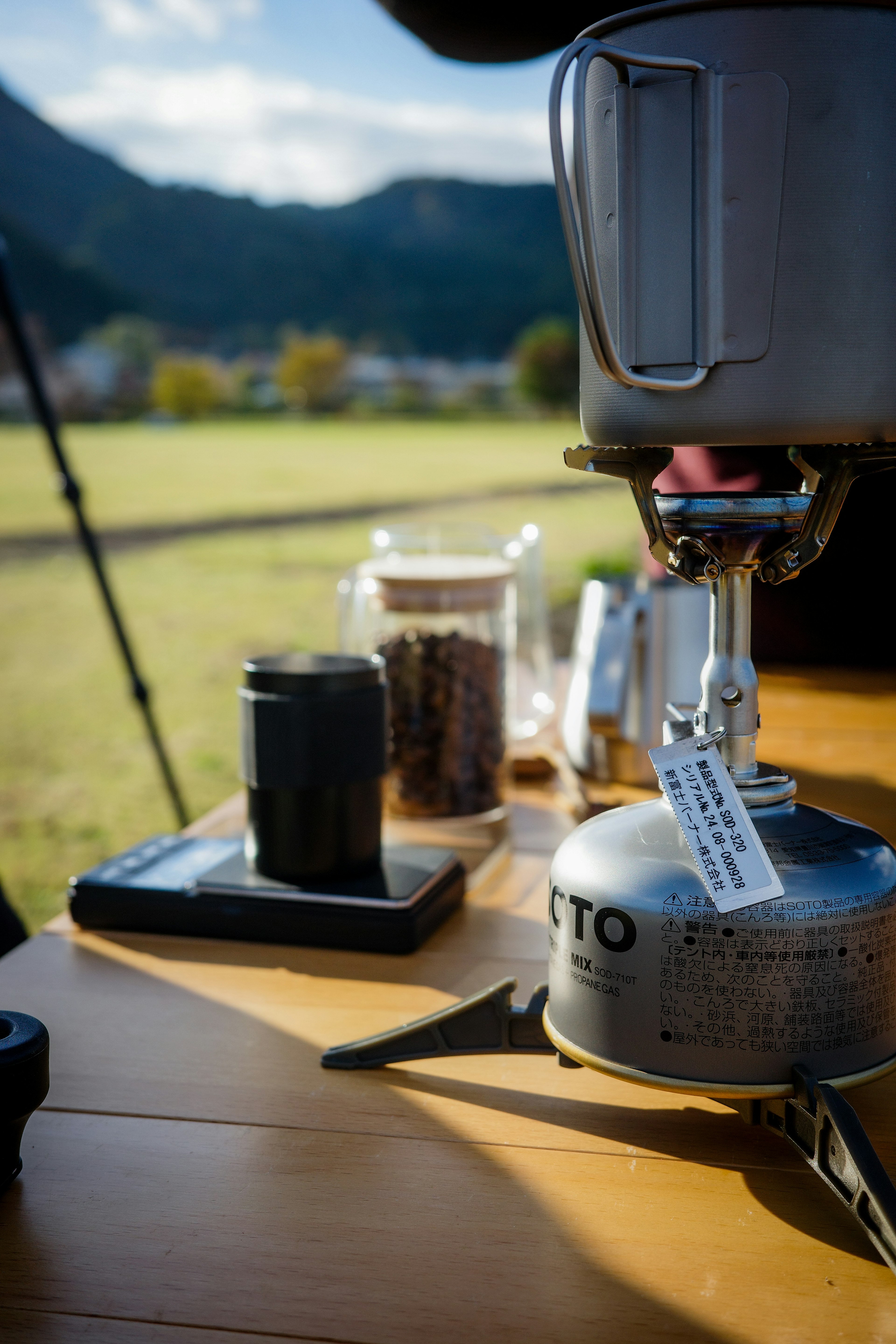 Estufa de camping con granos de café en una mesa de madera