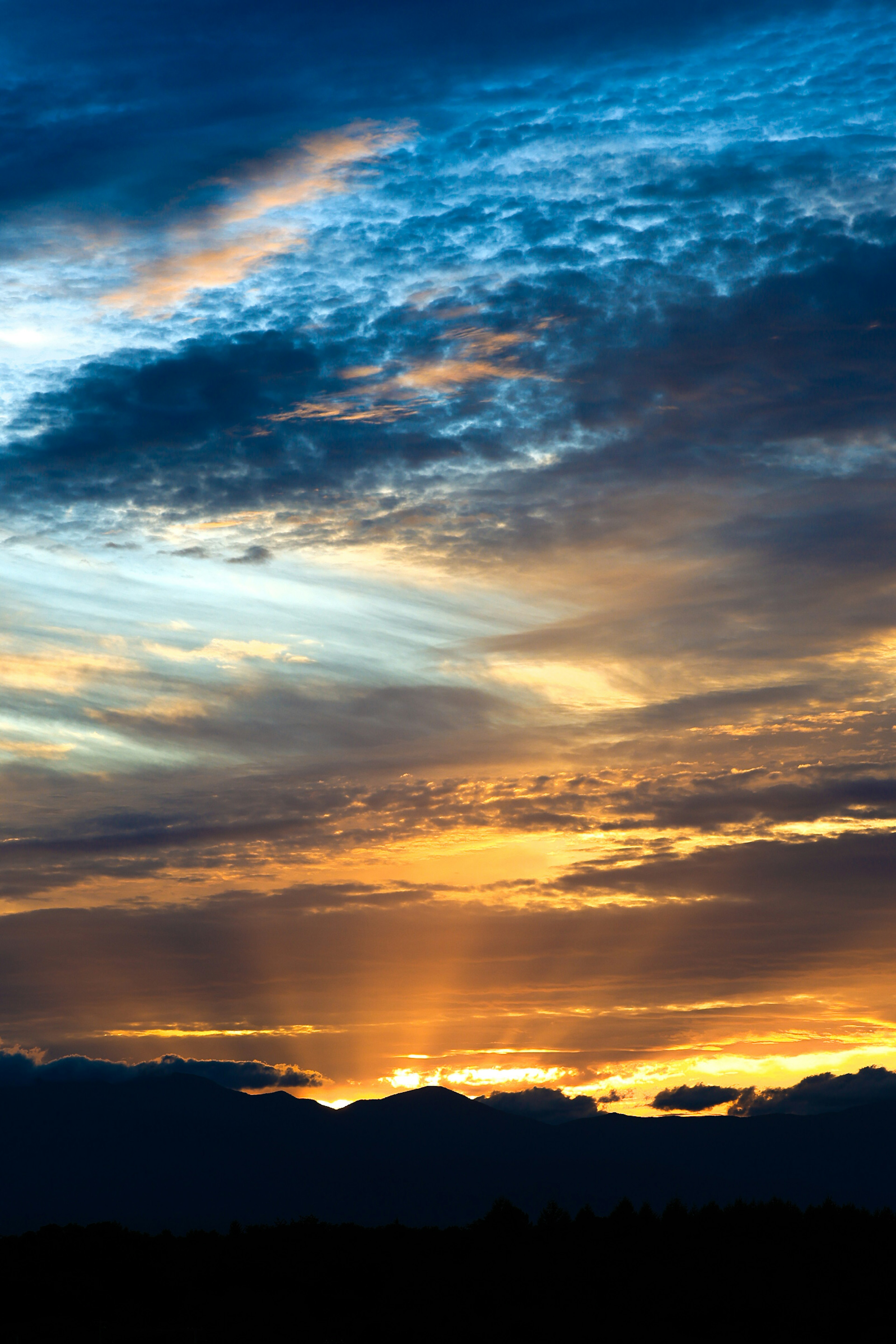 Ciel de coucher de soleil magnifique avec des nuages bleus et une lumière orange qui se croisent