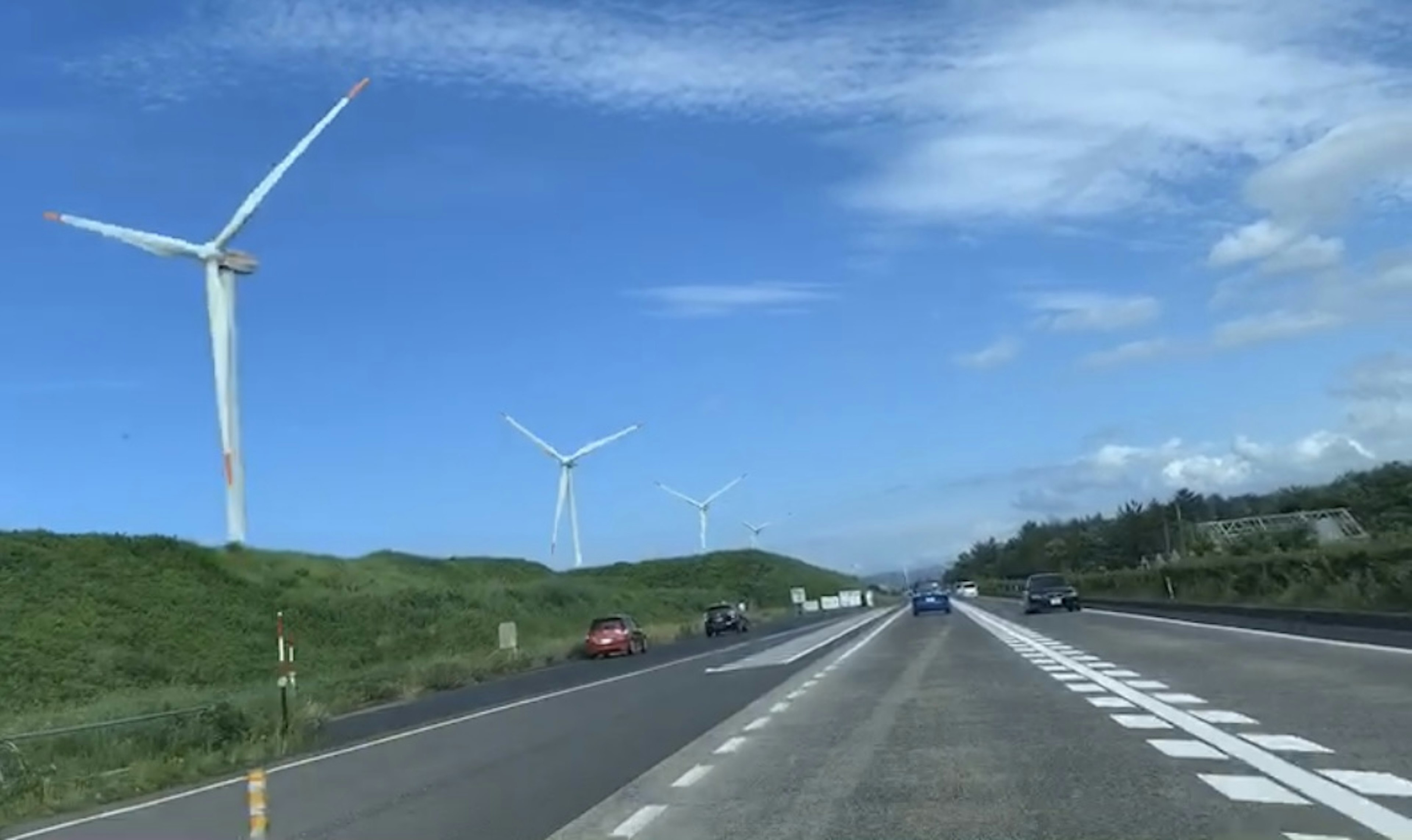 Highway with wind turbines under a blue sky