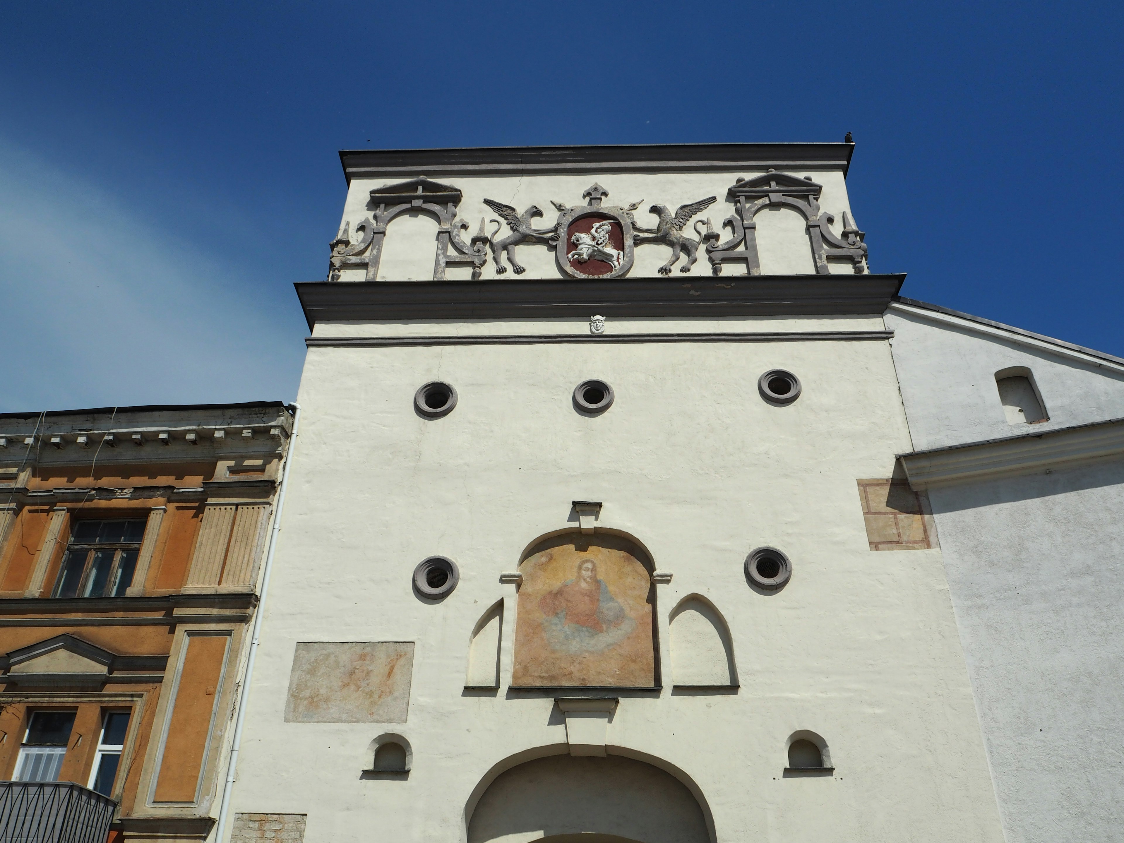 Un bâtiment aux murs blancs avec des arches décoratives et un blason