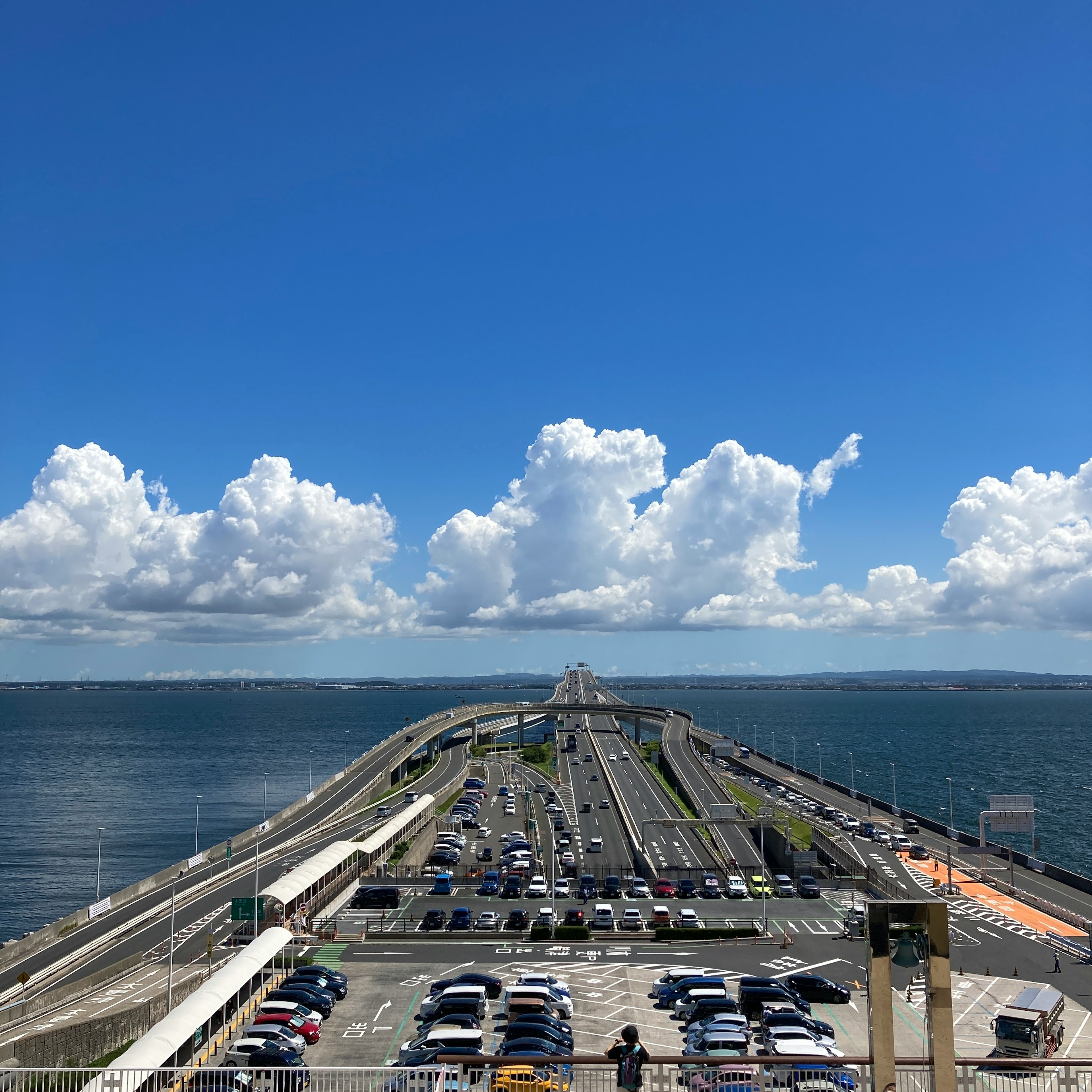 Lungo ponte che si estende sull'acqua con cielo azzurro e nuvole bianche