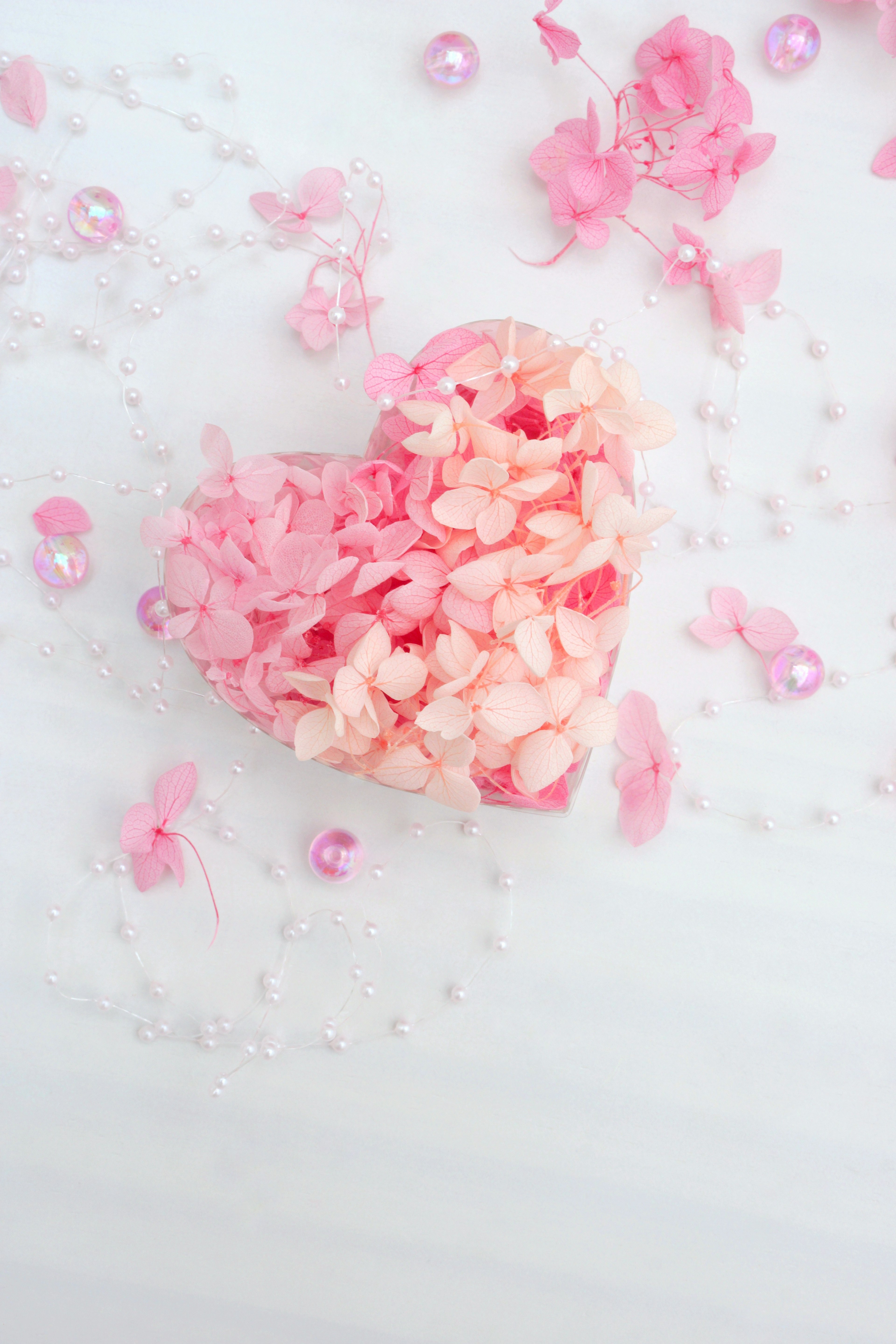 Heart shape made of pink flower petals surrounded by decorative petals