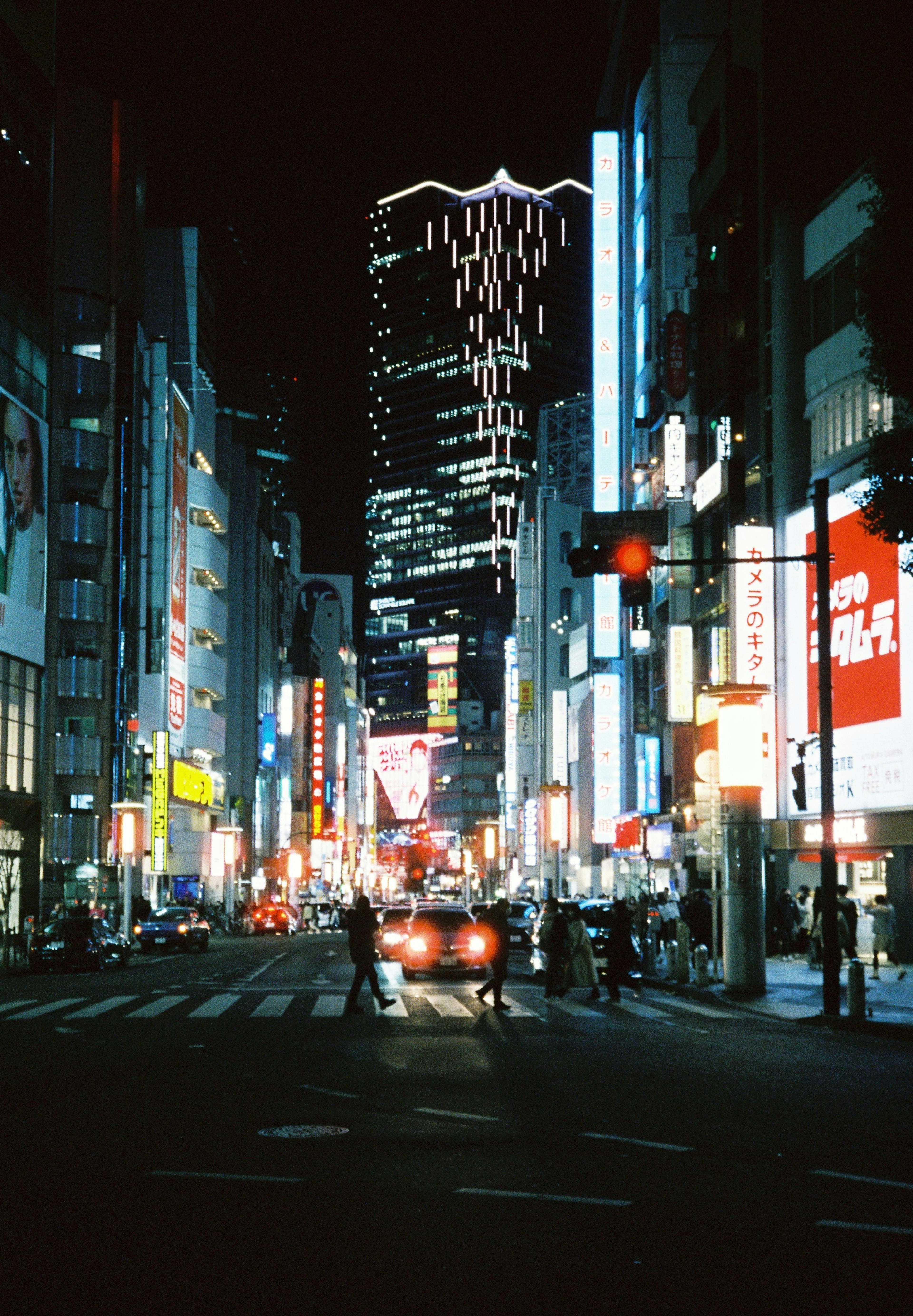 Paysage urbain nocturne avec des gratte-ciel et des néons et des personnes traversant l'intersection