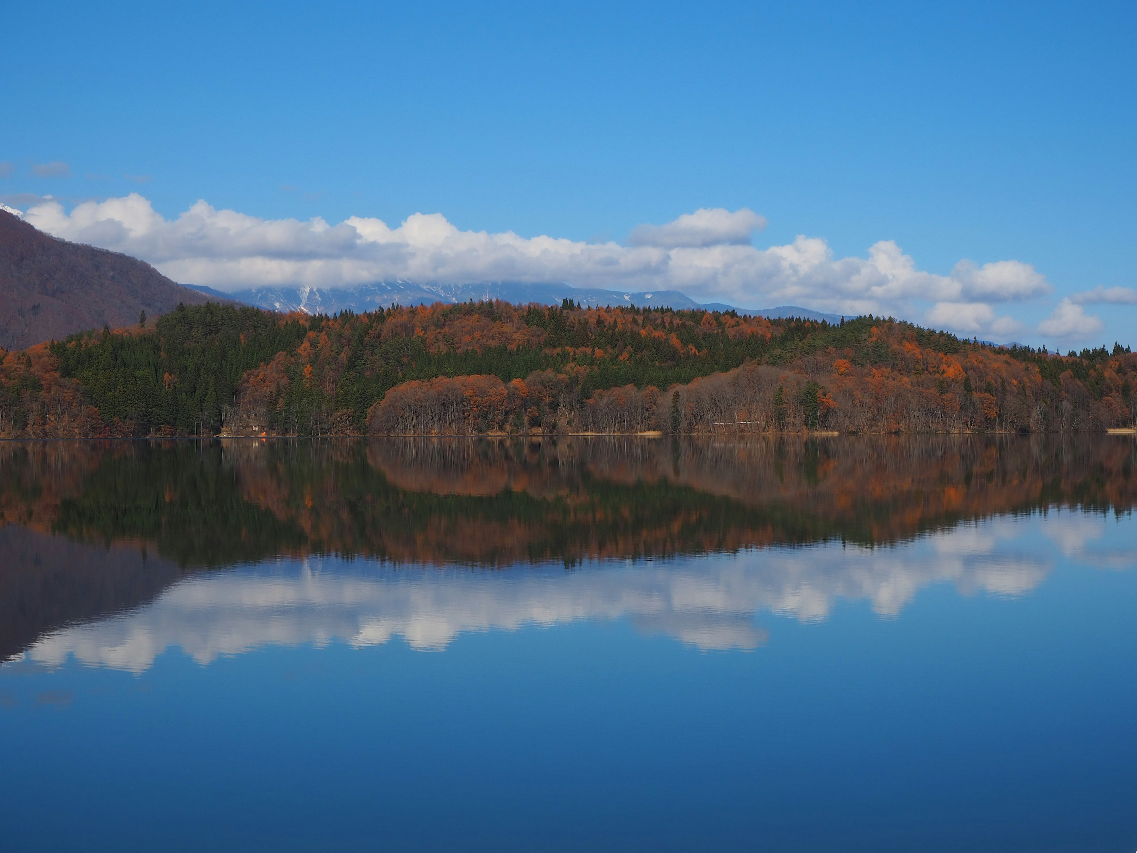 Serene lake reflecting autumn colors and blue sky