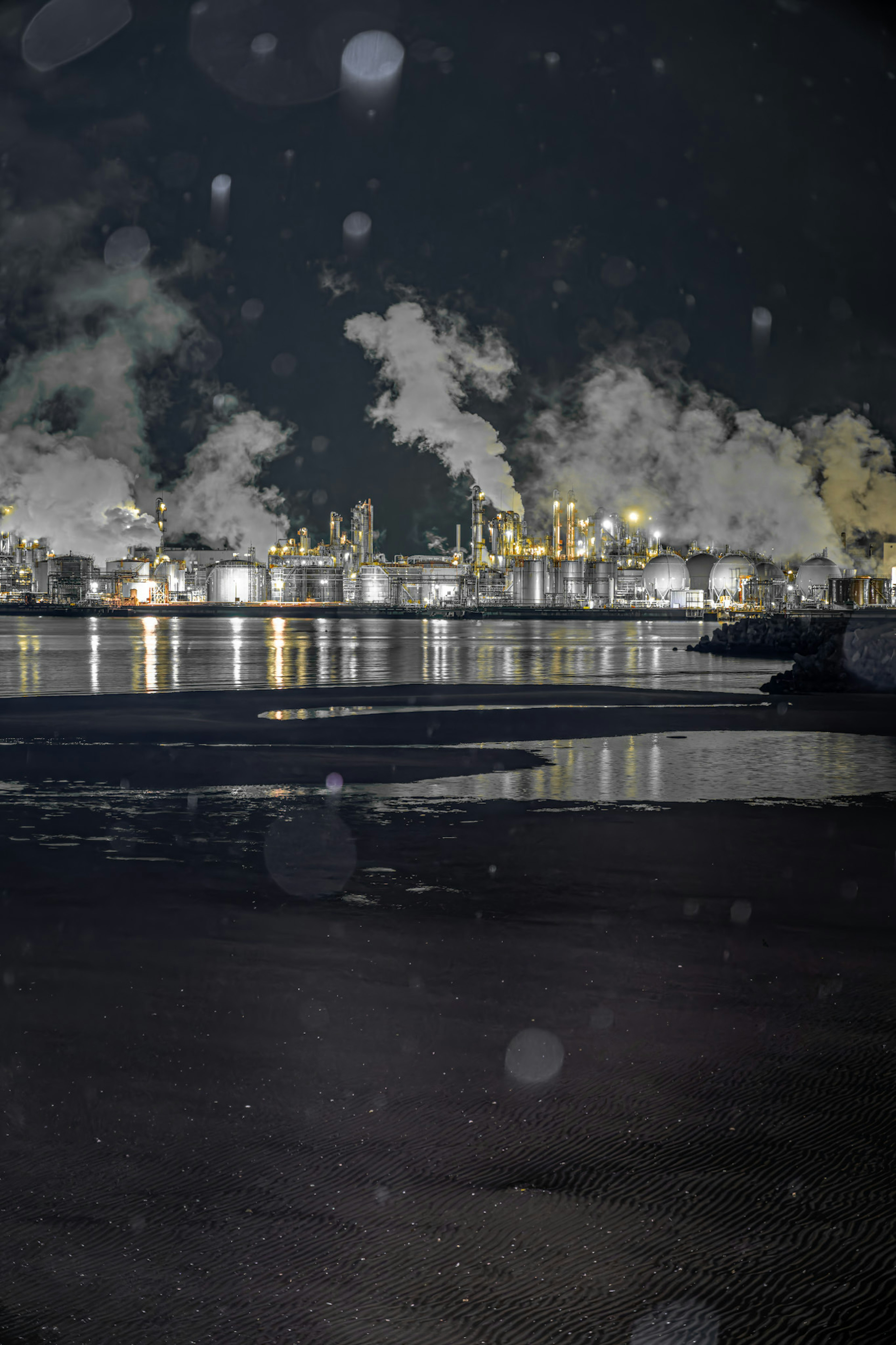 Night view of an industrial area with smoke and reflections