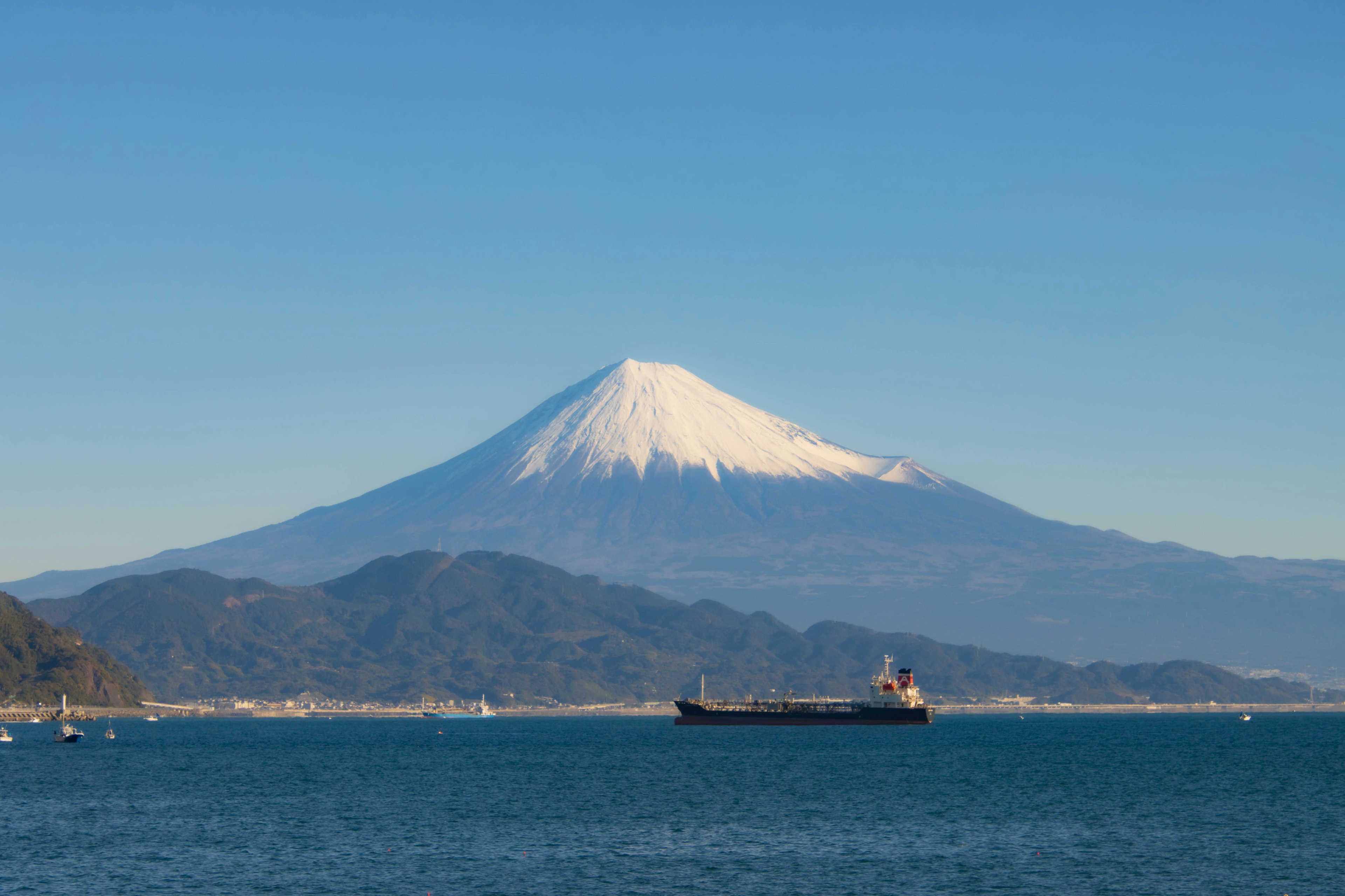 Vista escénica del Monte Fuji cubierto de nieve con un barco navegando en el mar