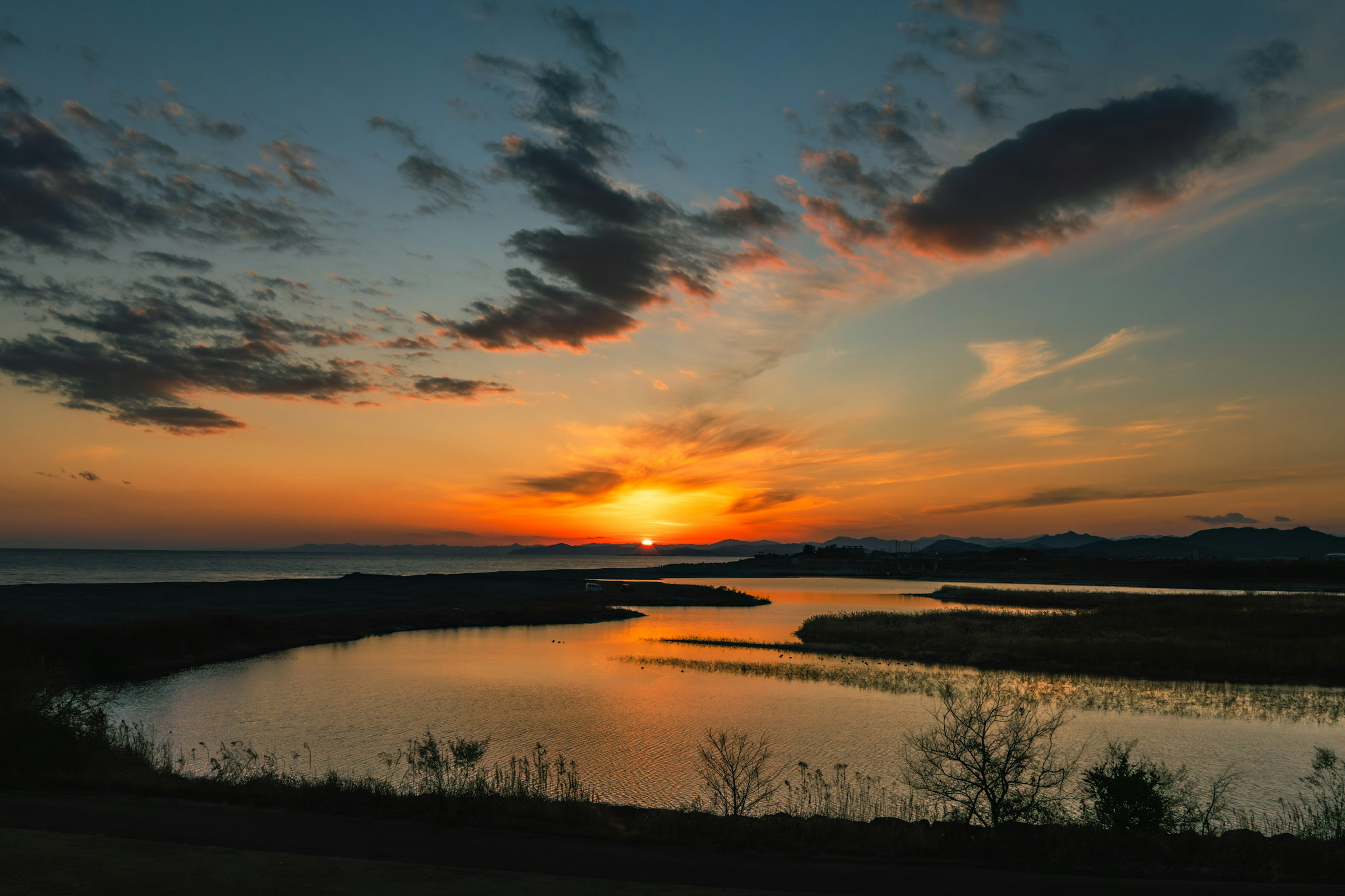 Magnifique coucher de soleil se reflétant sur l'eau avec une rivière et de l'herbe visibles