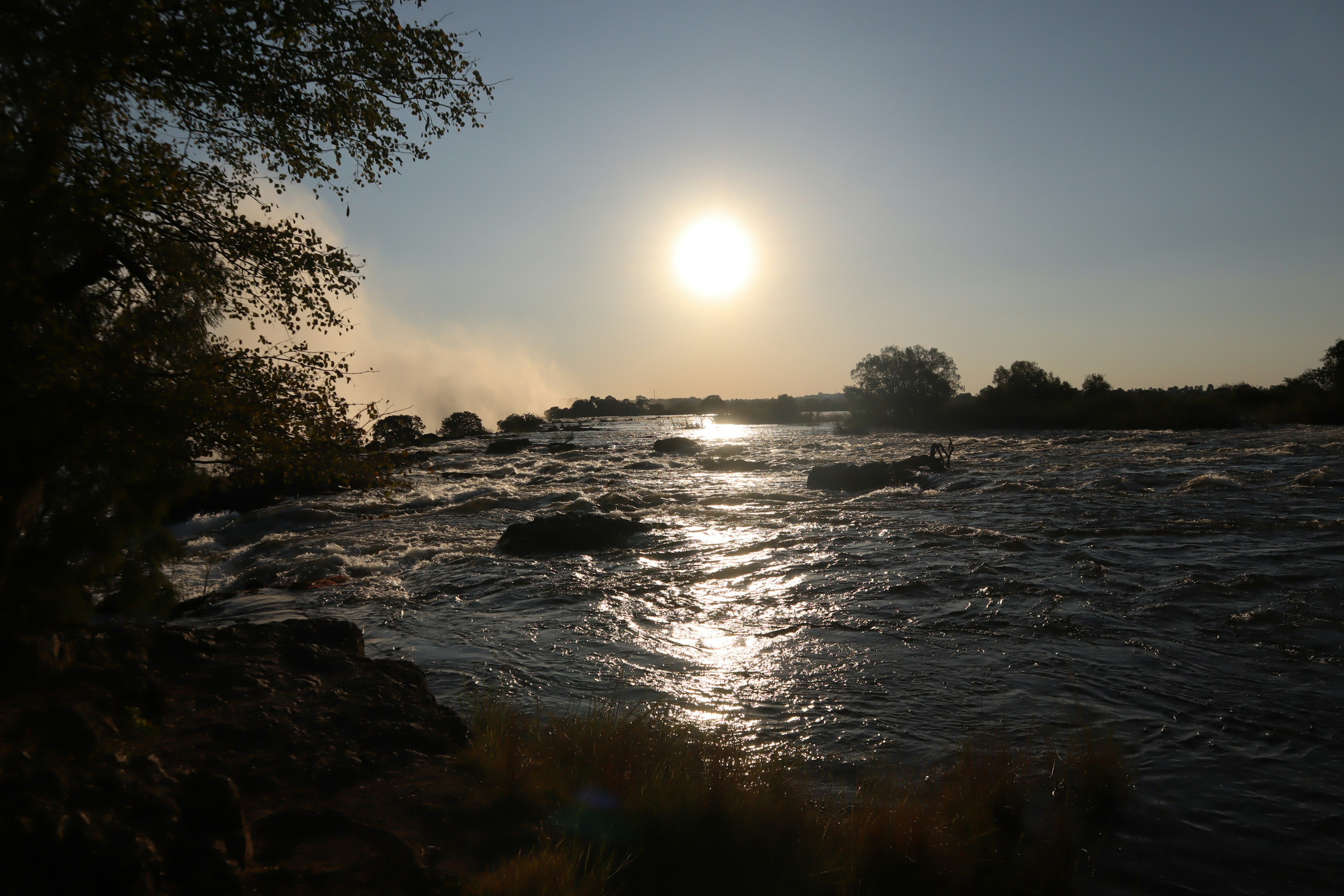 Paisaje fluvial escénico con atardecer Sol reflejándose en el agua y las rocas