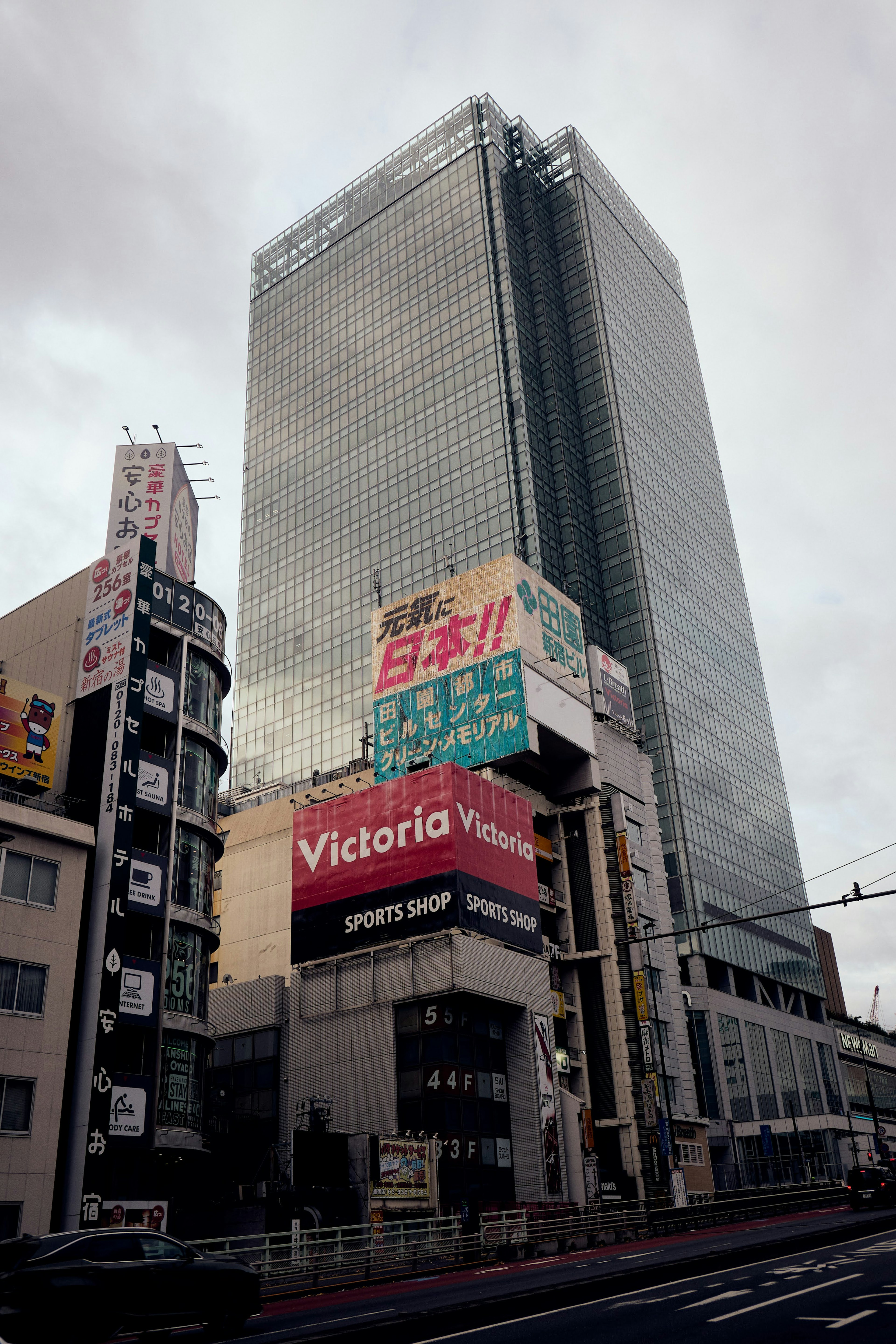 Urban landscape featuring a tall skyscraper and commercial buildings with glass facade and advertising signs