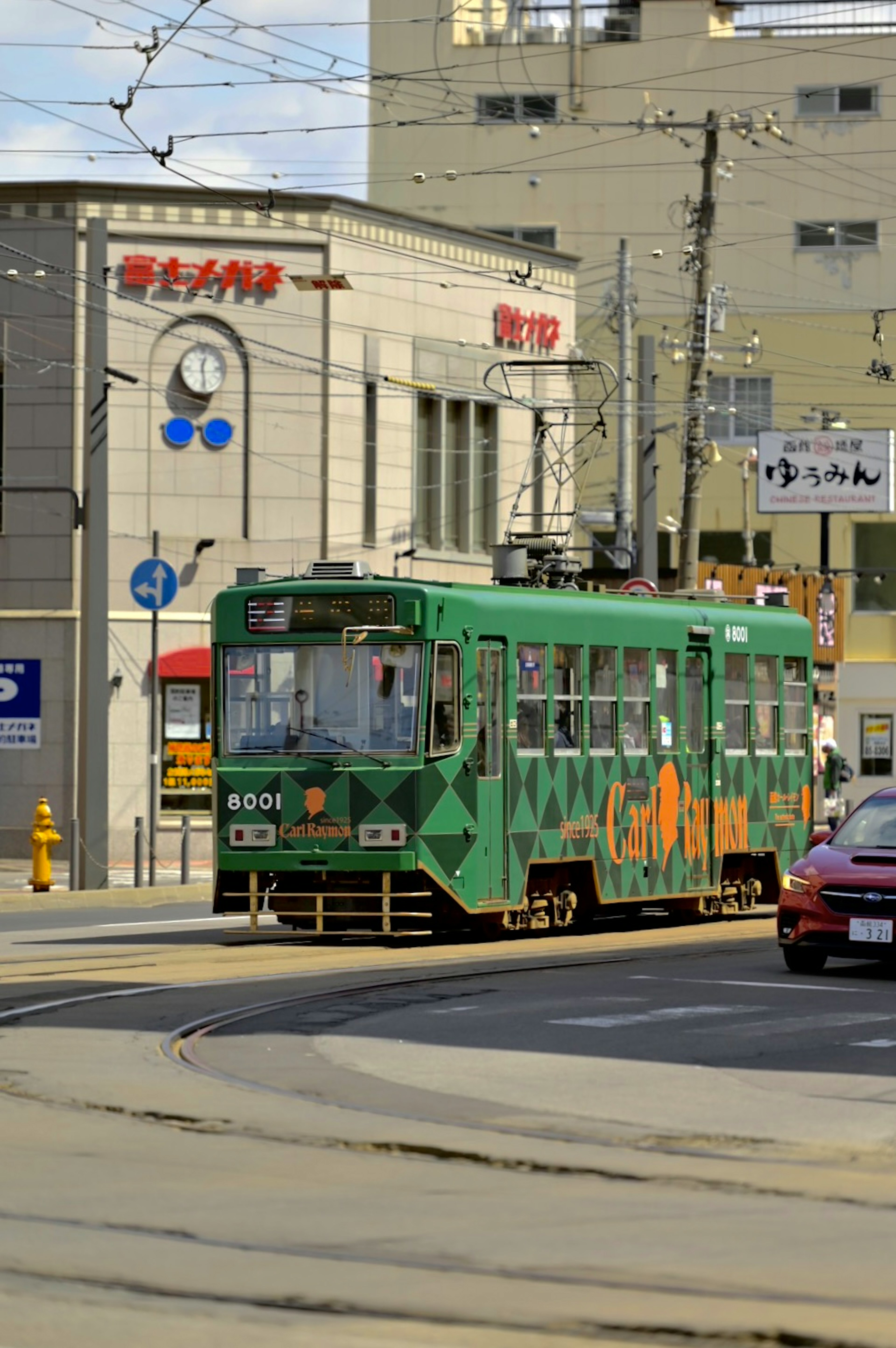 Green tram turning on the street with buildings in the background