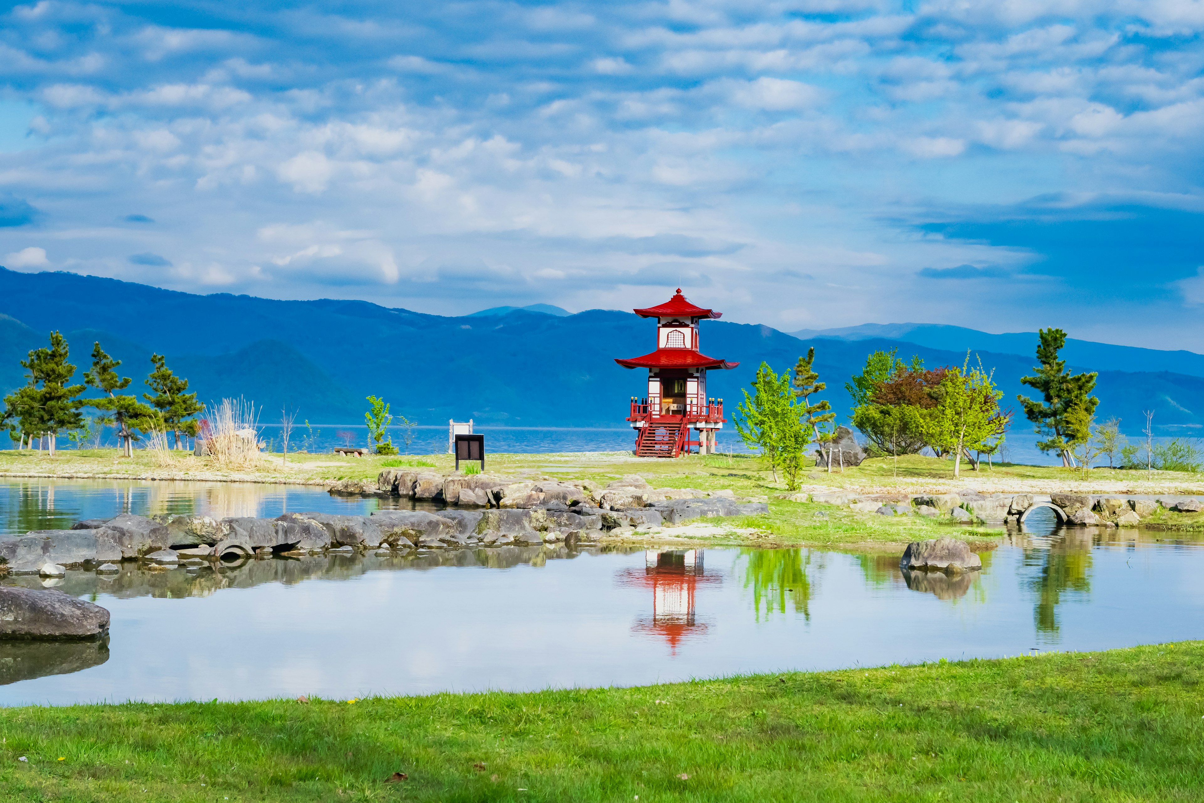 Vista panoramica di un parco con un padiglione rosso e un lago tranquillo