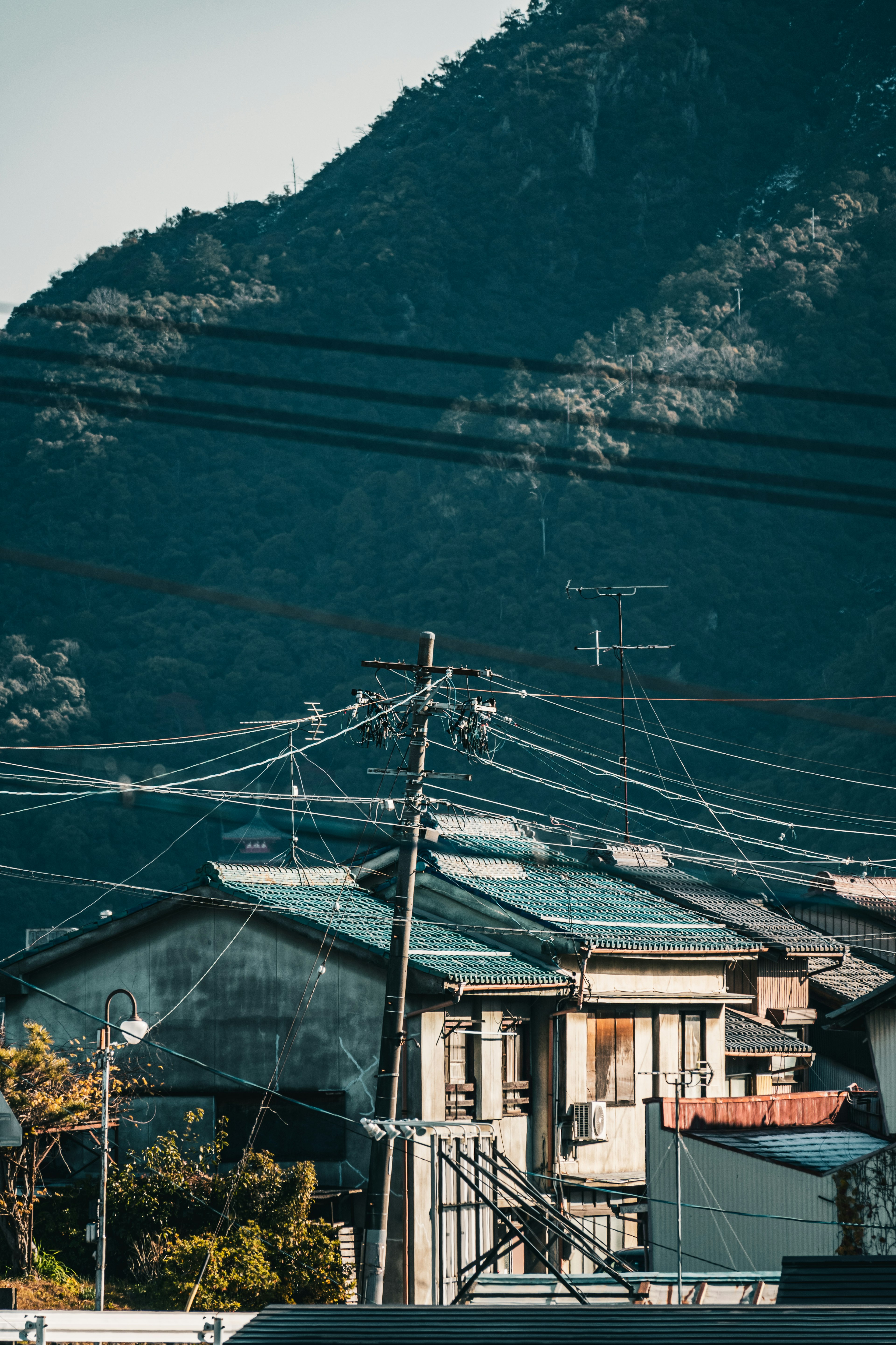 A view of houses with power lines in the foreground and mountains in the background