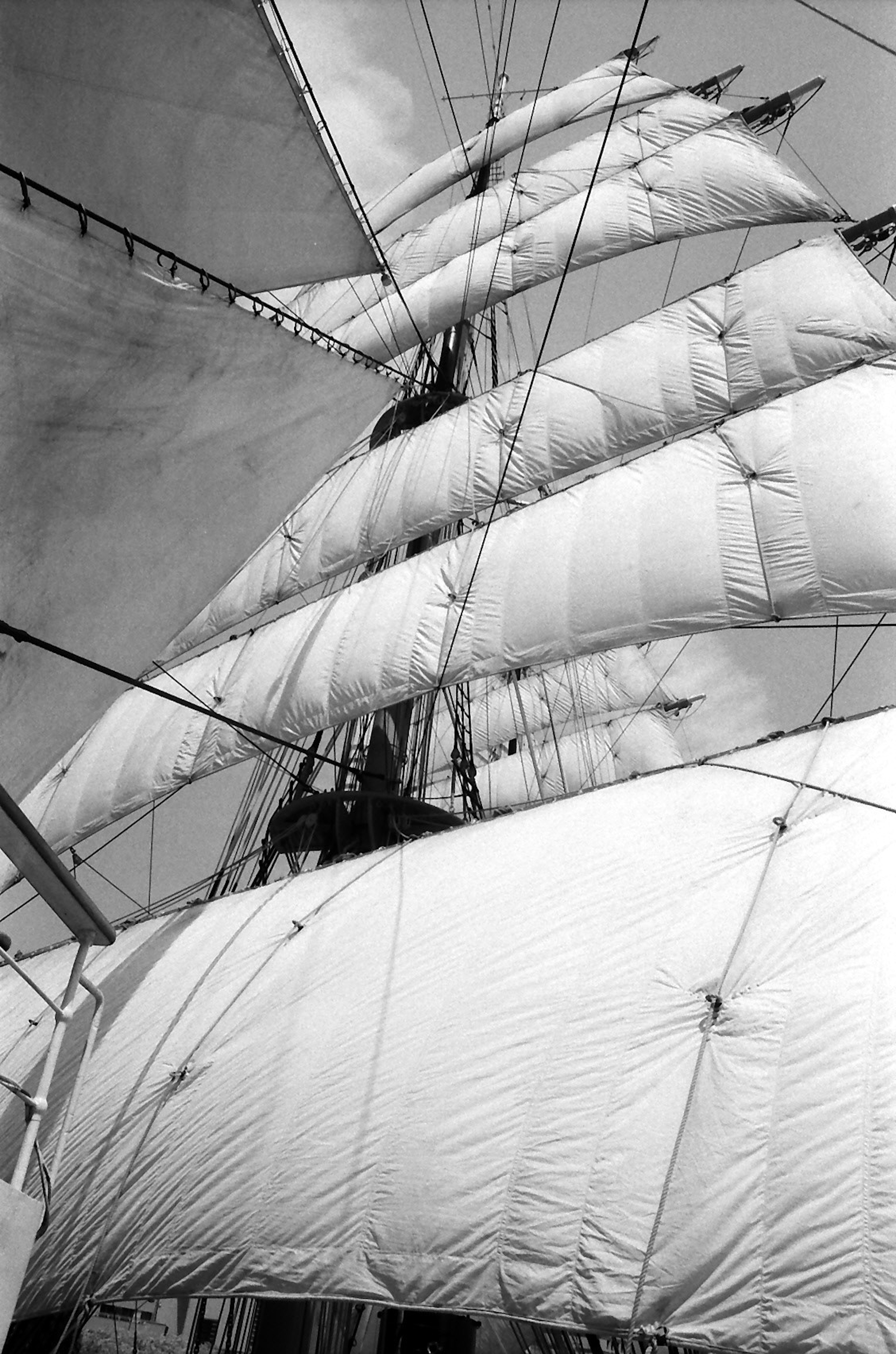 Image en noir et blanc d'un grand voilier avec des voiles déployées contre le ciel