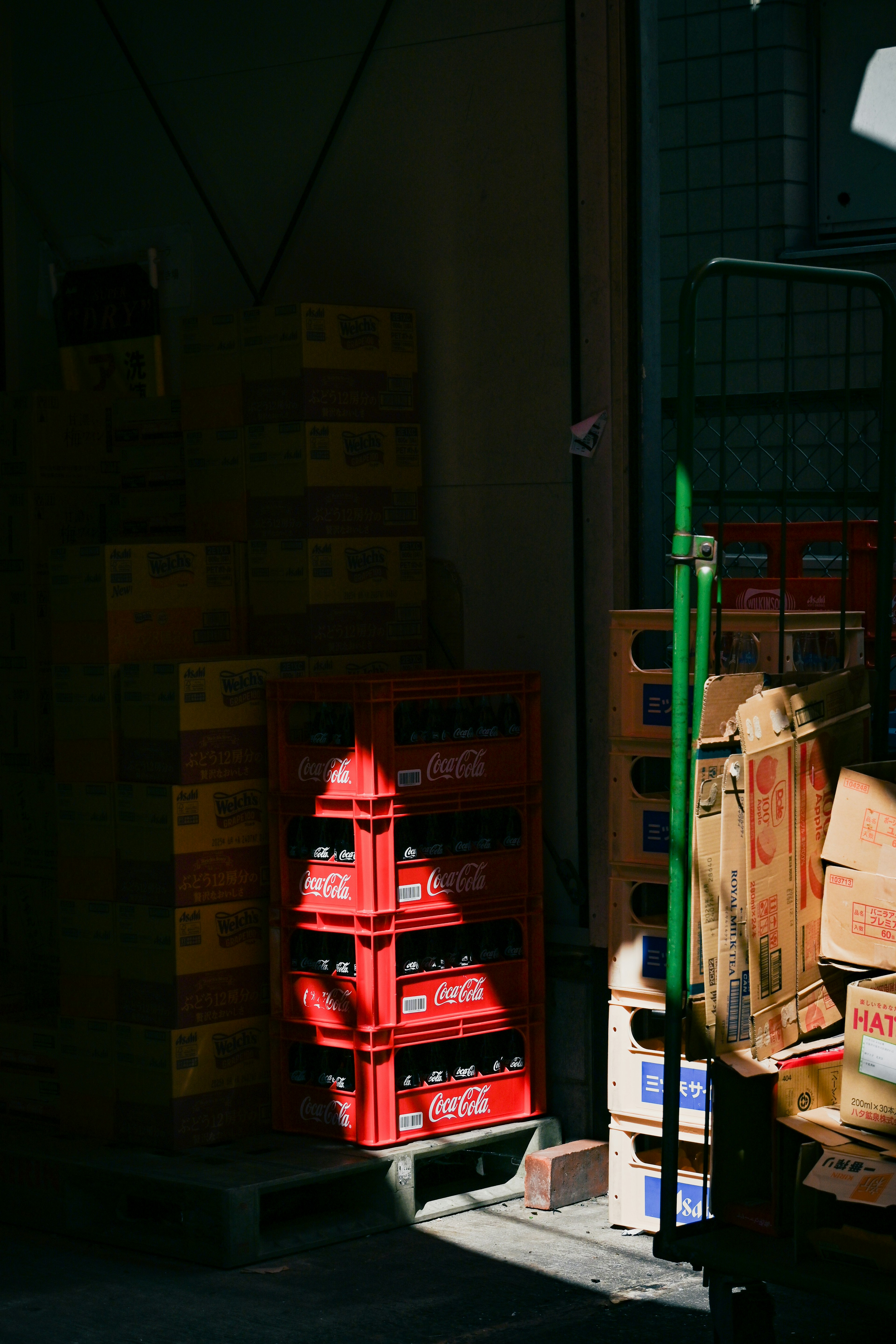 Caisses rouges empilées dans une zone faiblement éclairée avec des caisses en bois