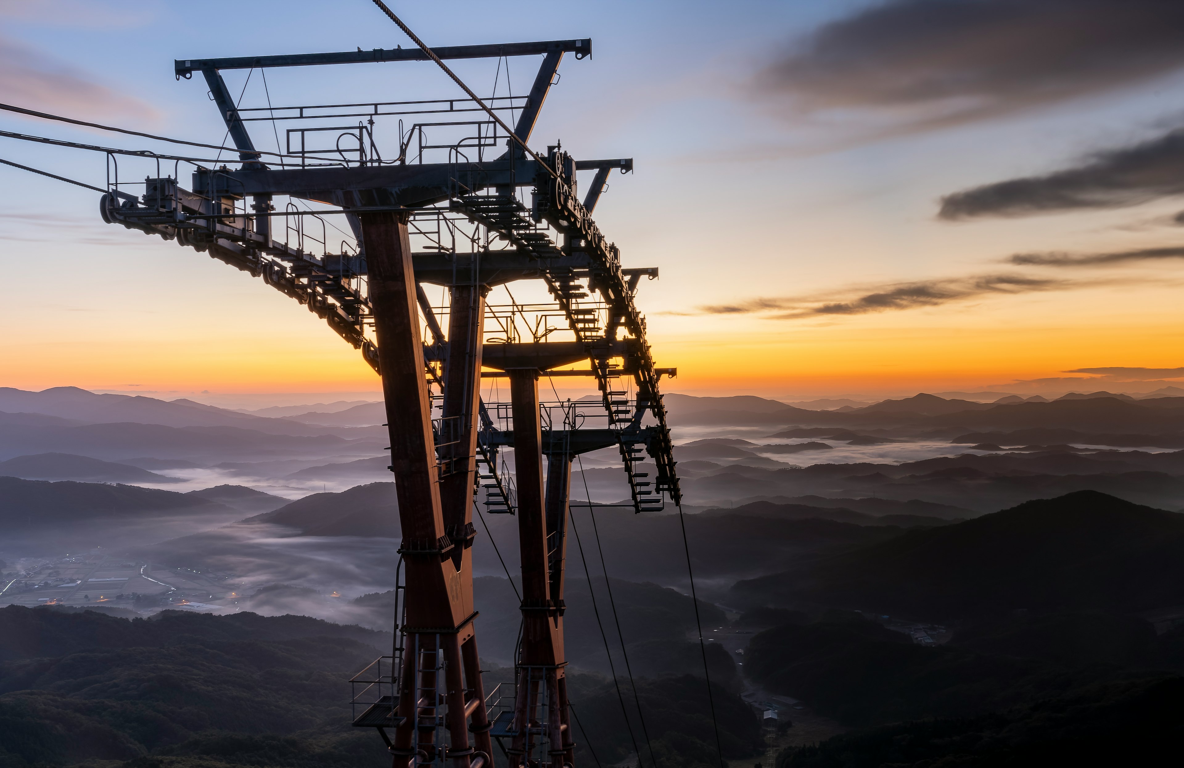 Pylônes de téléphérique au lever du soleil sur des montagnes