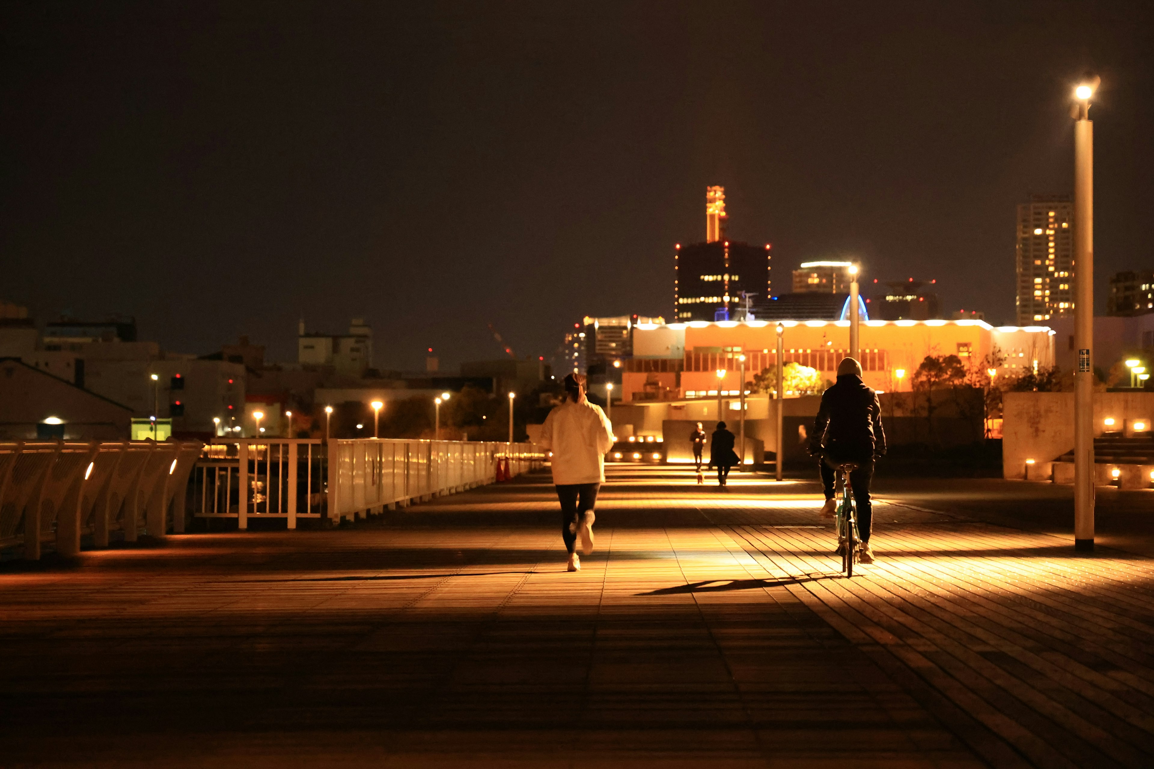 Personas caminando y montando en bicicleta en un paseo urbano de noche