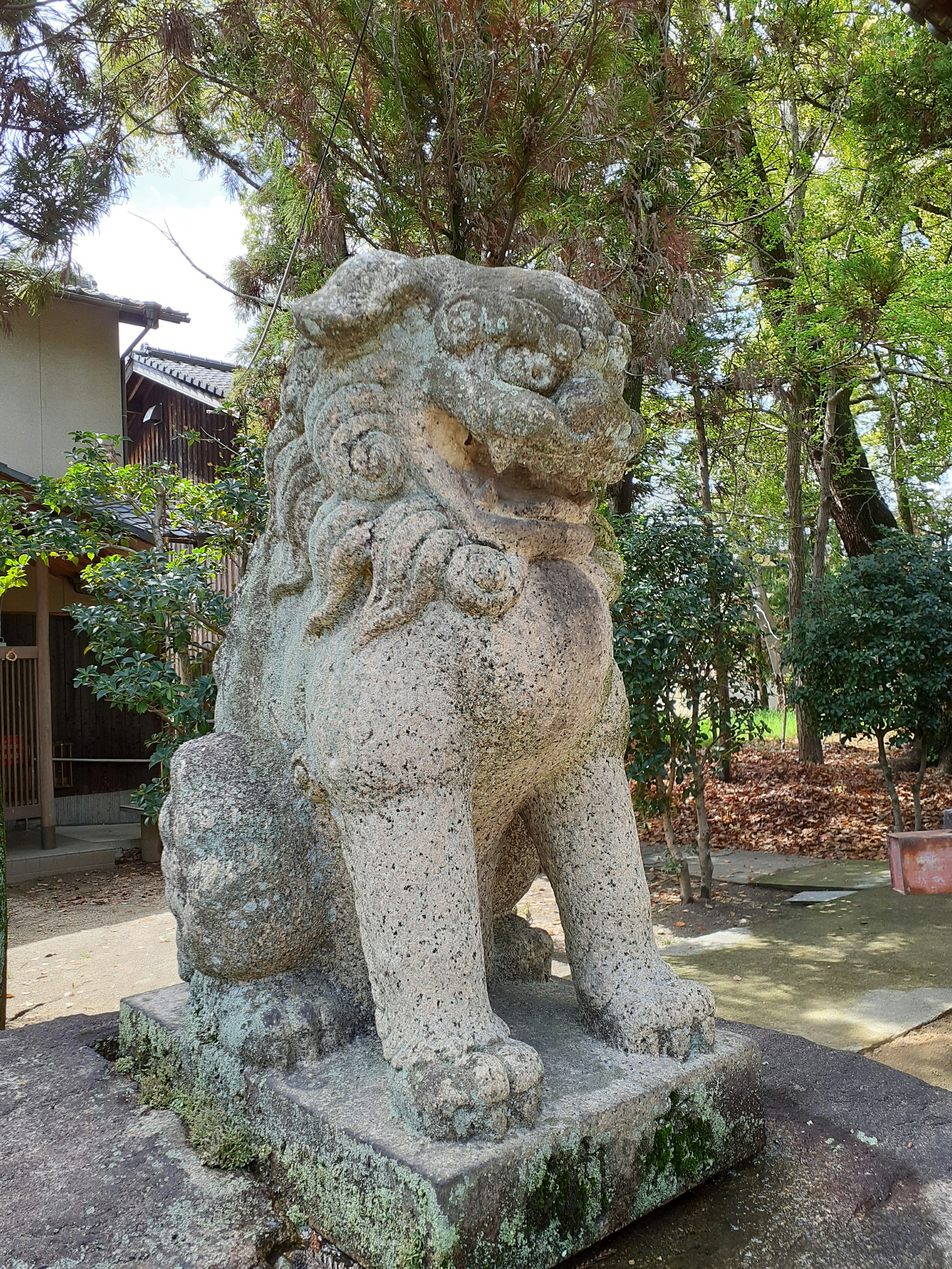 Stone lion statue standing in a garden surrounded by greenery