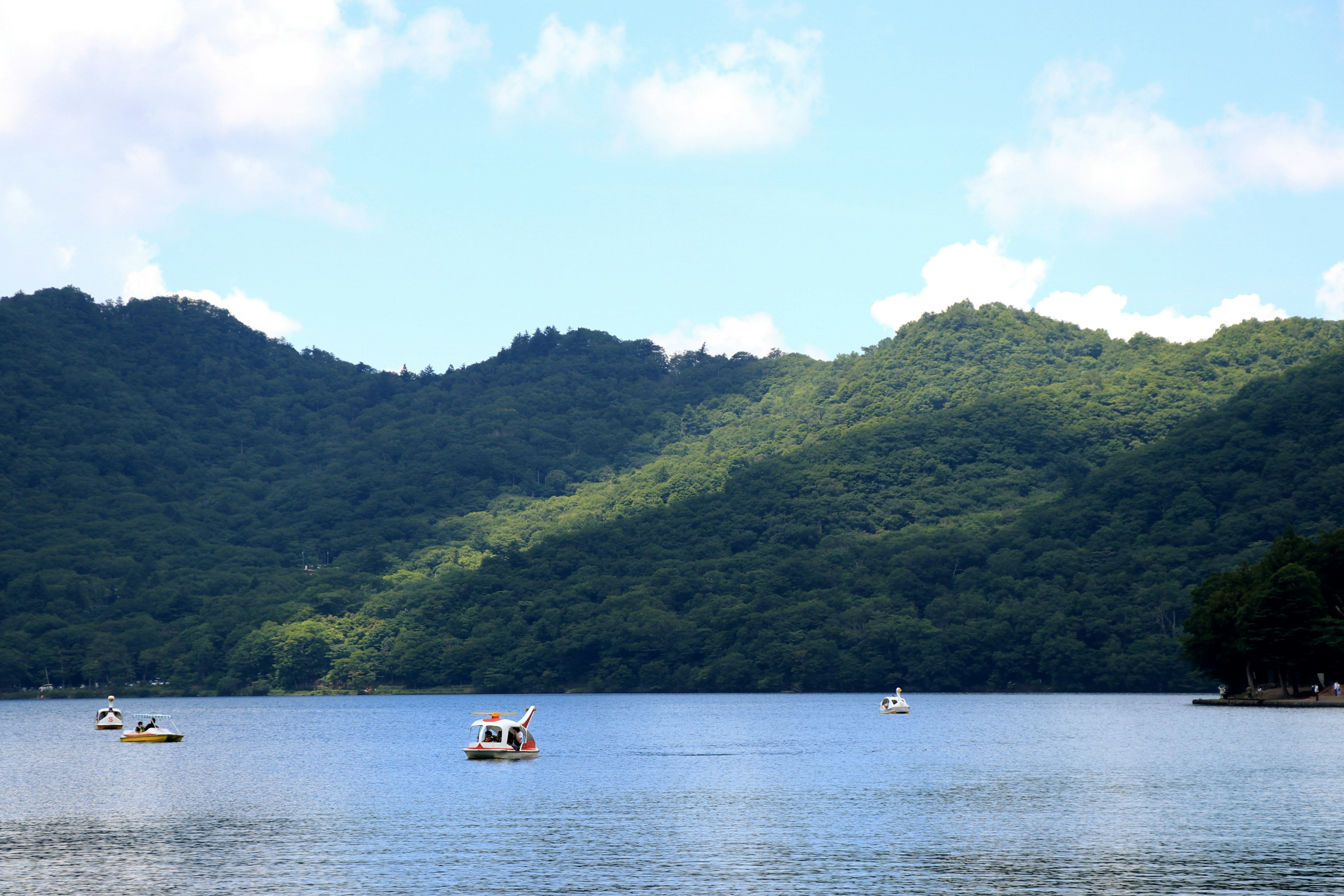 寧靜的湖景，漂浮著小船和郁郁蔥蔥的山脈