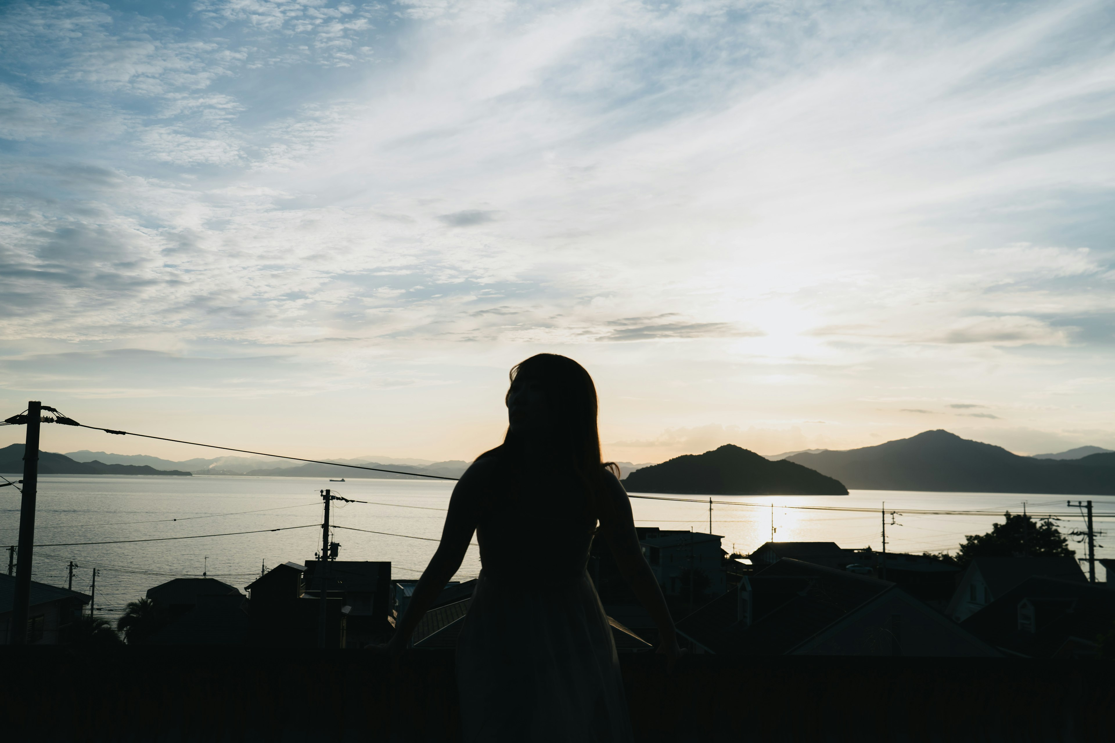 夕日を背景にした女性のシルエットと海の風景