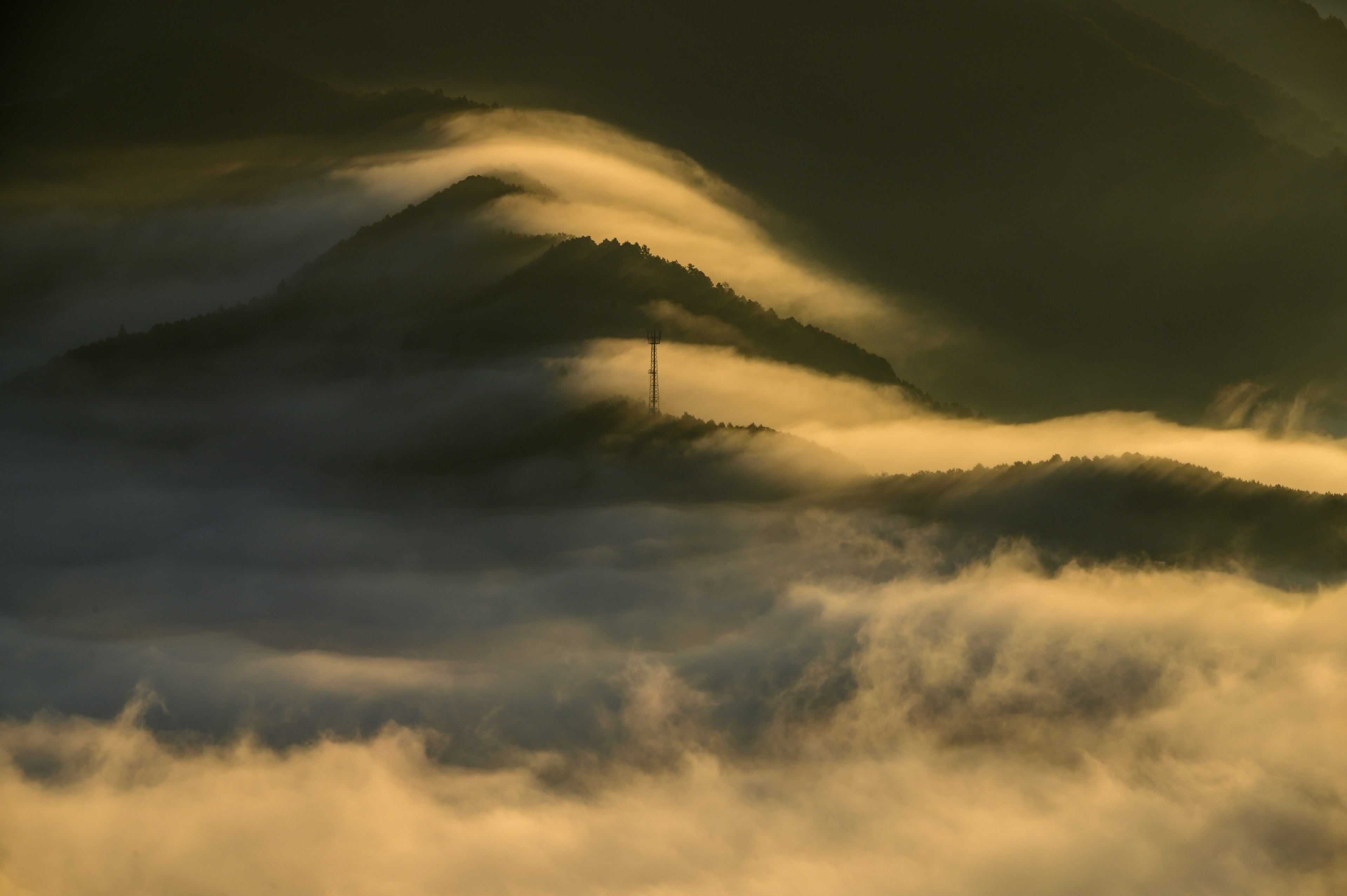 Silhouette d'une montagne enveloppée de brume avec des vagues de lumière douce