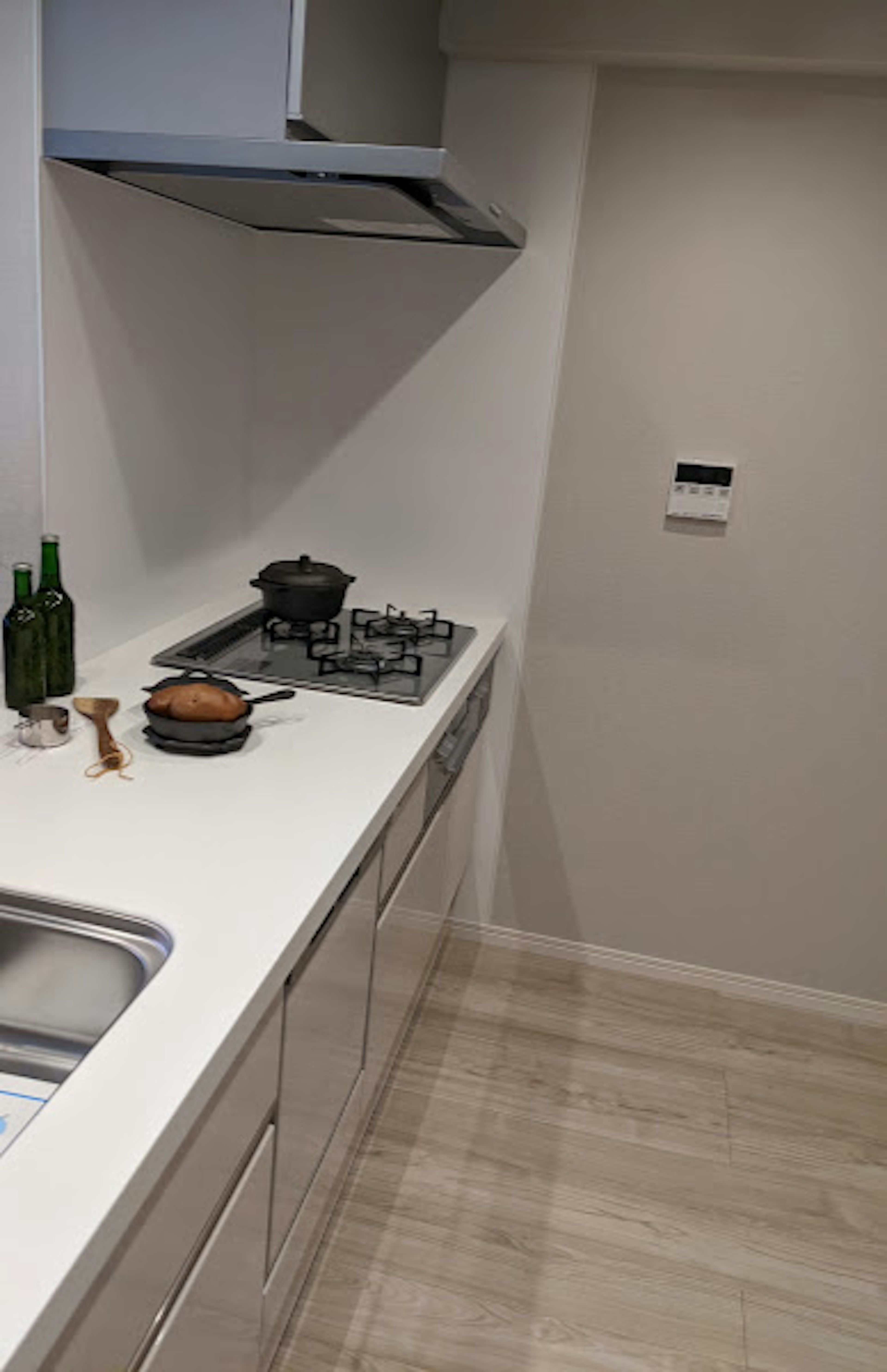 Modern kitchen with white countertop featuring a pot and green bottles