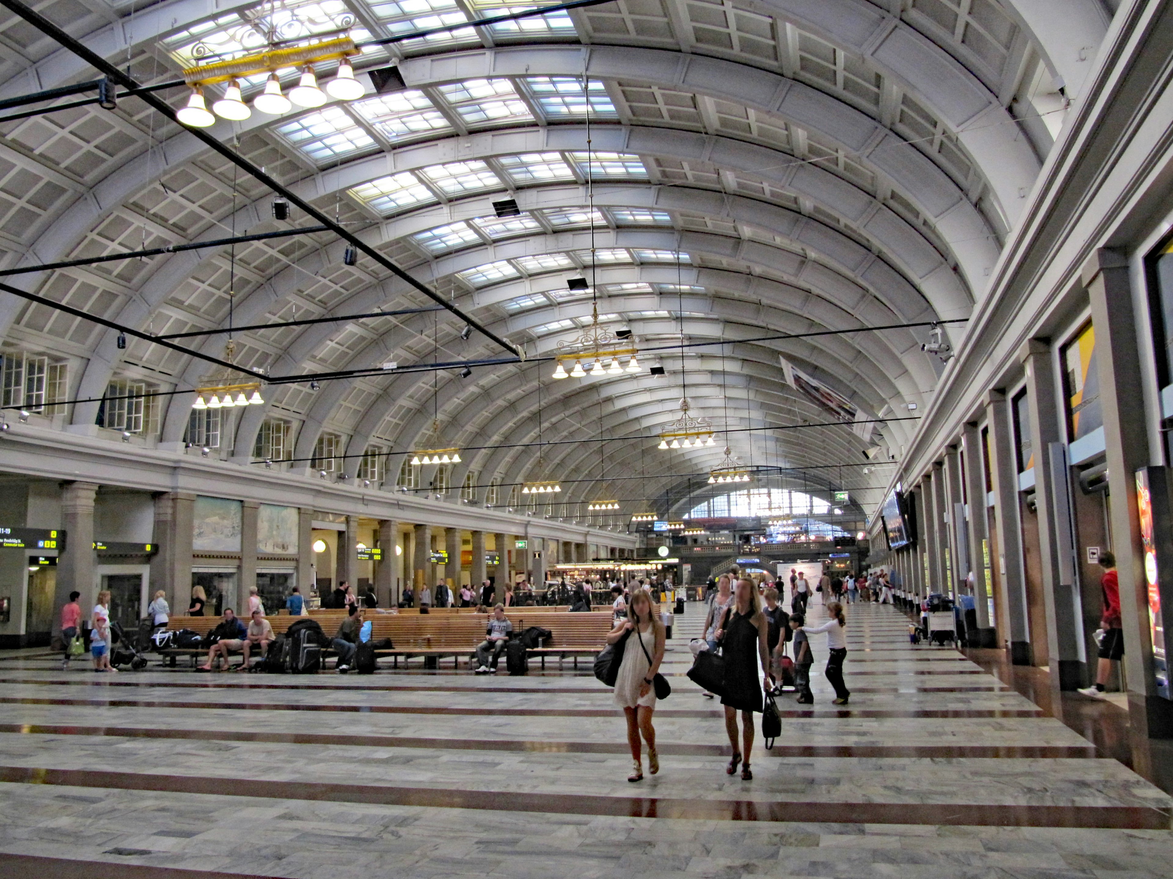 Intérieur spacieux d'une gare avec un plafond voûté et de grandes fenêtres lumineuses