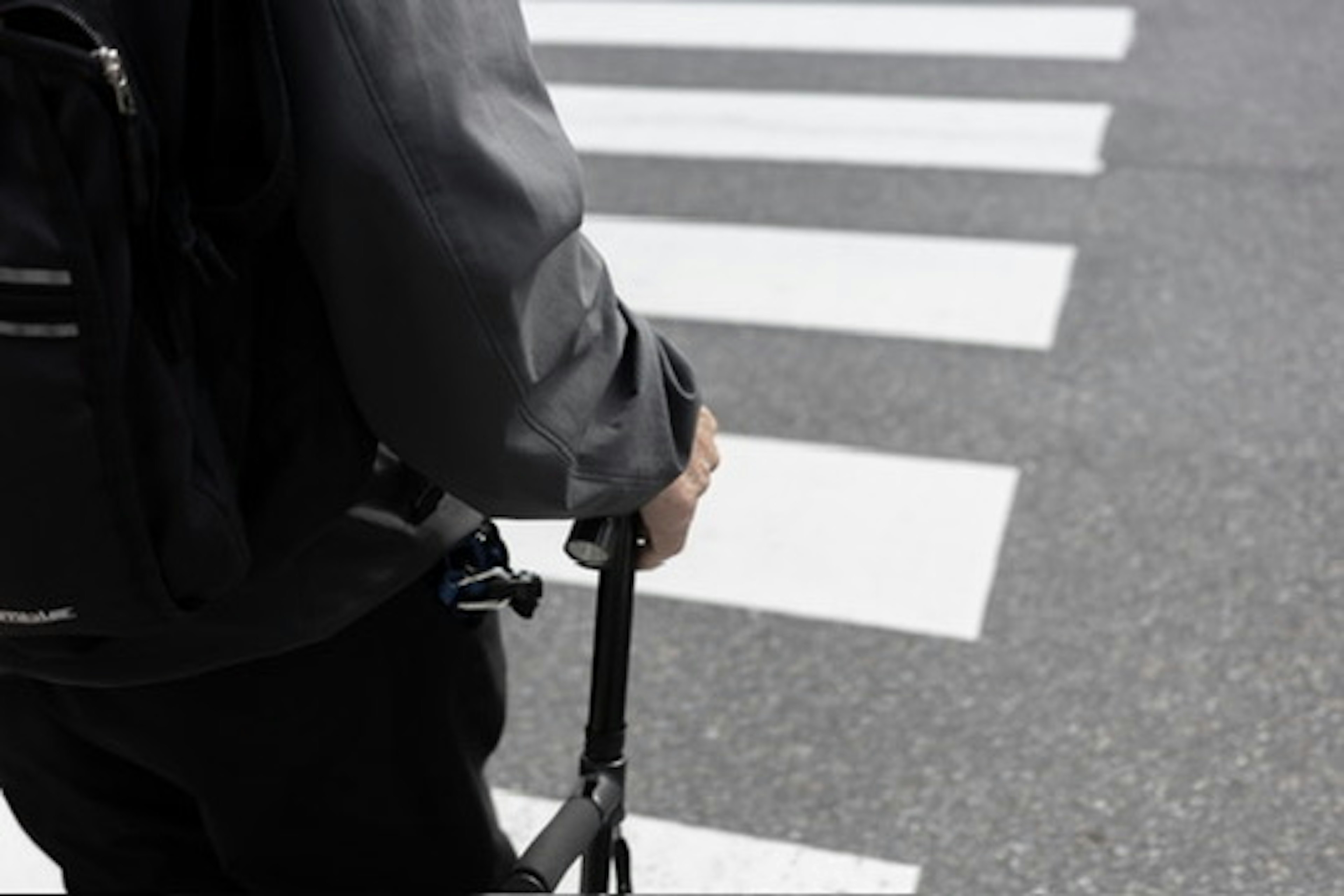 Person, der einen Kinderwagen an einem Zebrastreifen hält