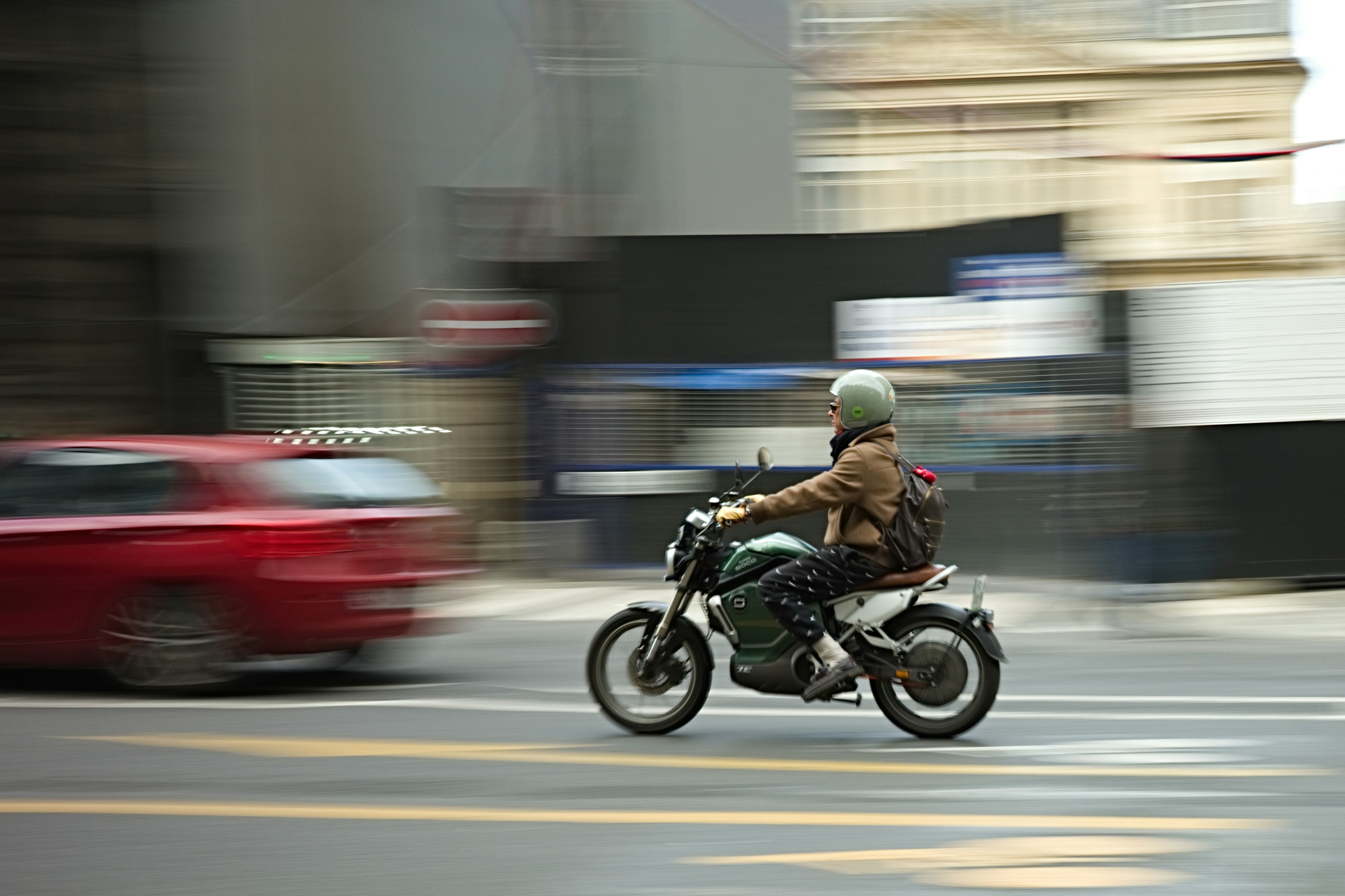 A man riding a motorcycle swiftly through the city