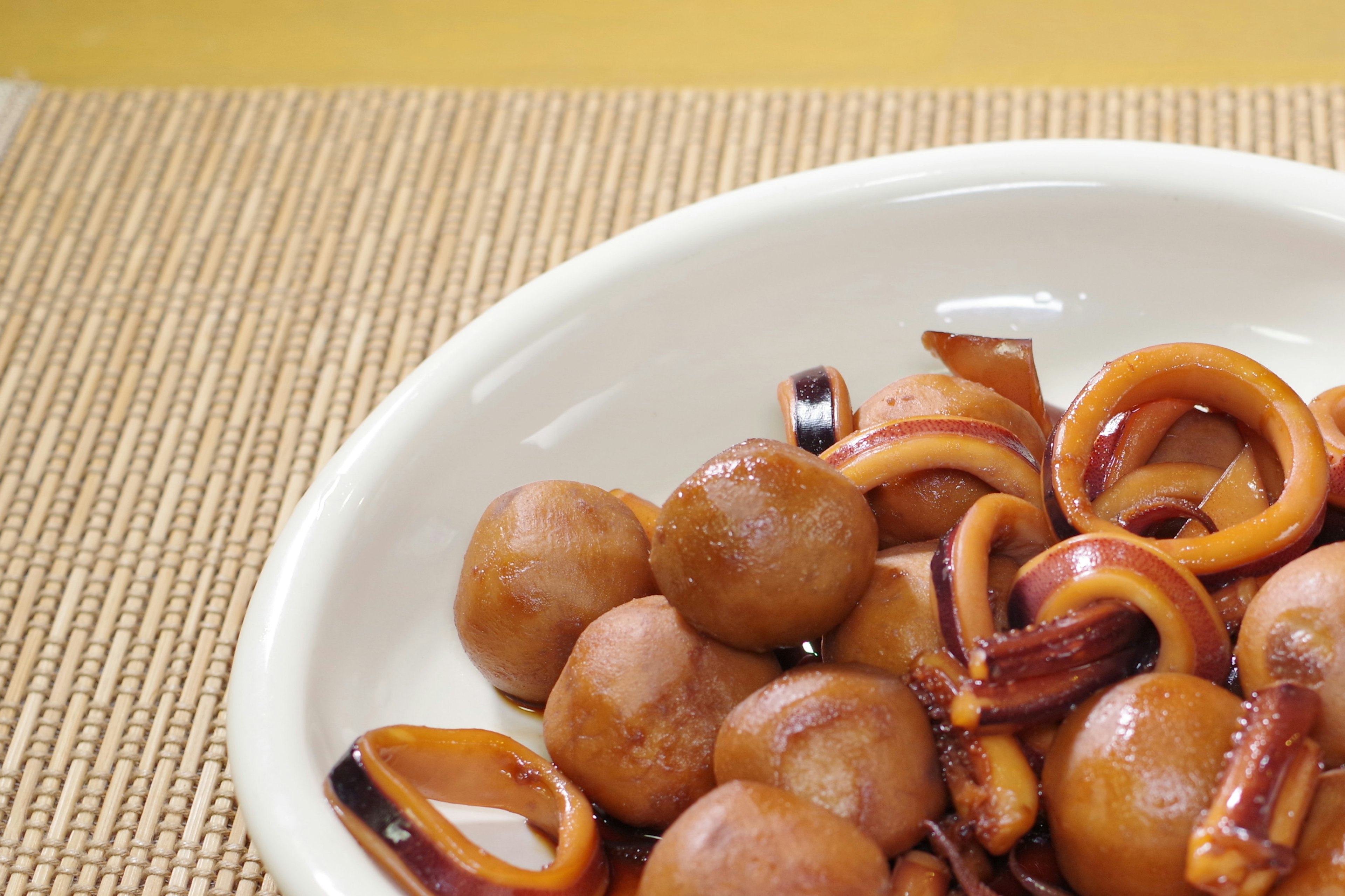 Brown squid rings and ball-shaped food served in a white bowl