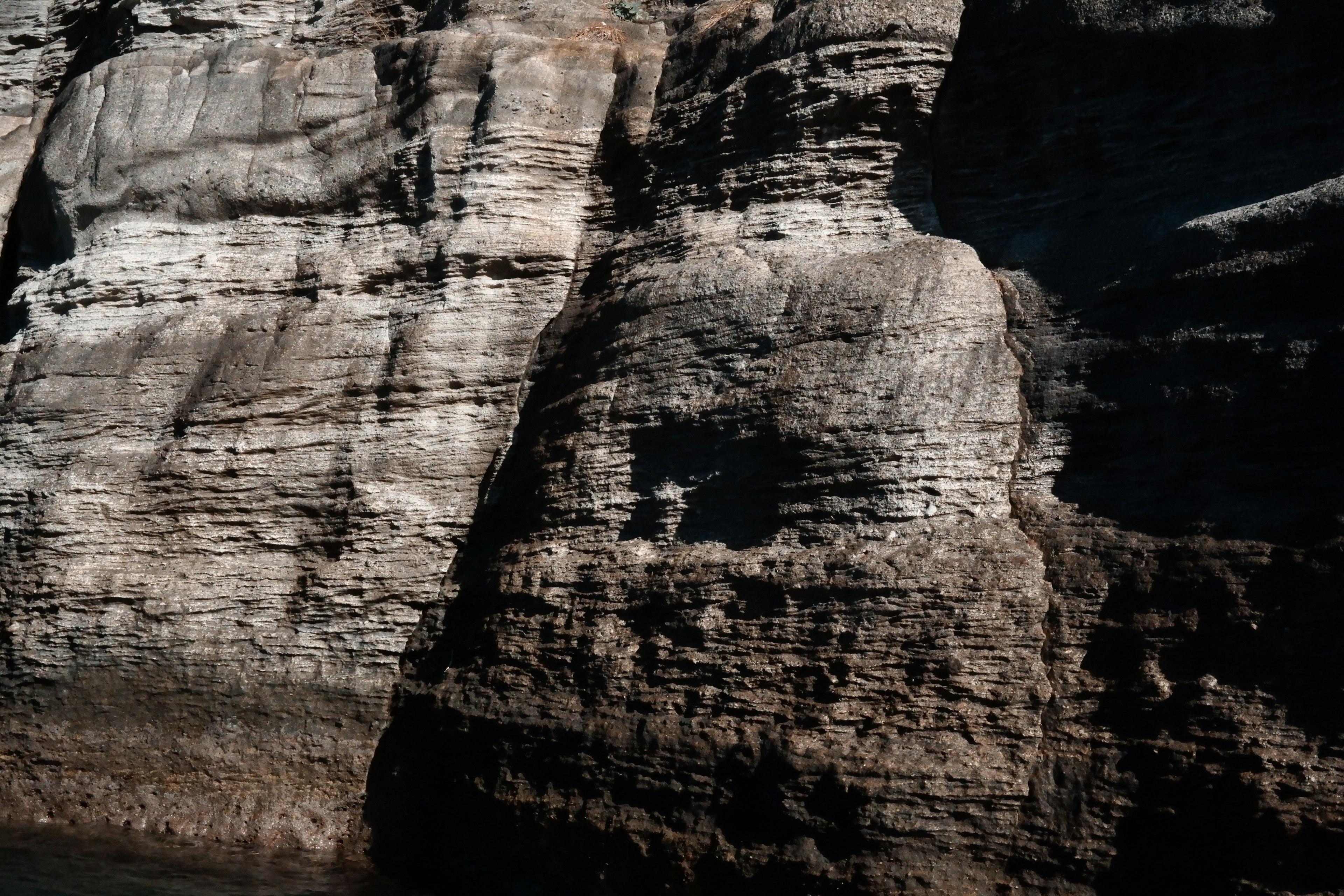 Layered rock cliff with dark tones and textured patterns