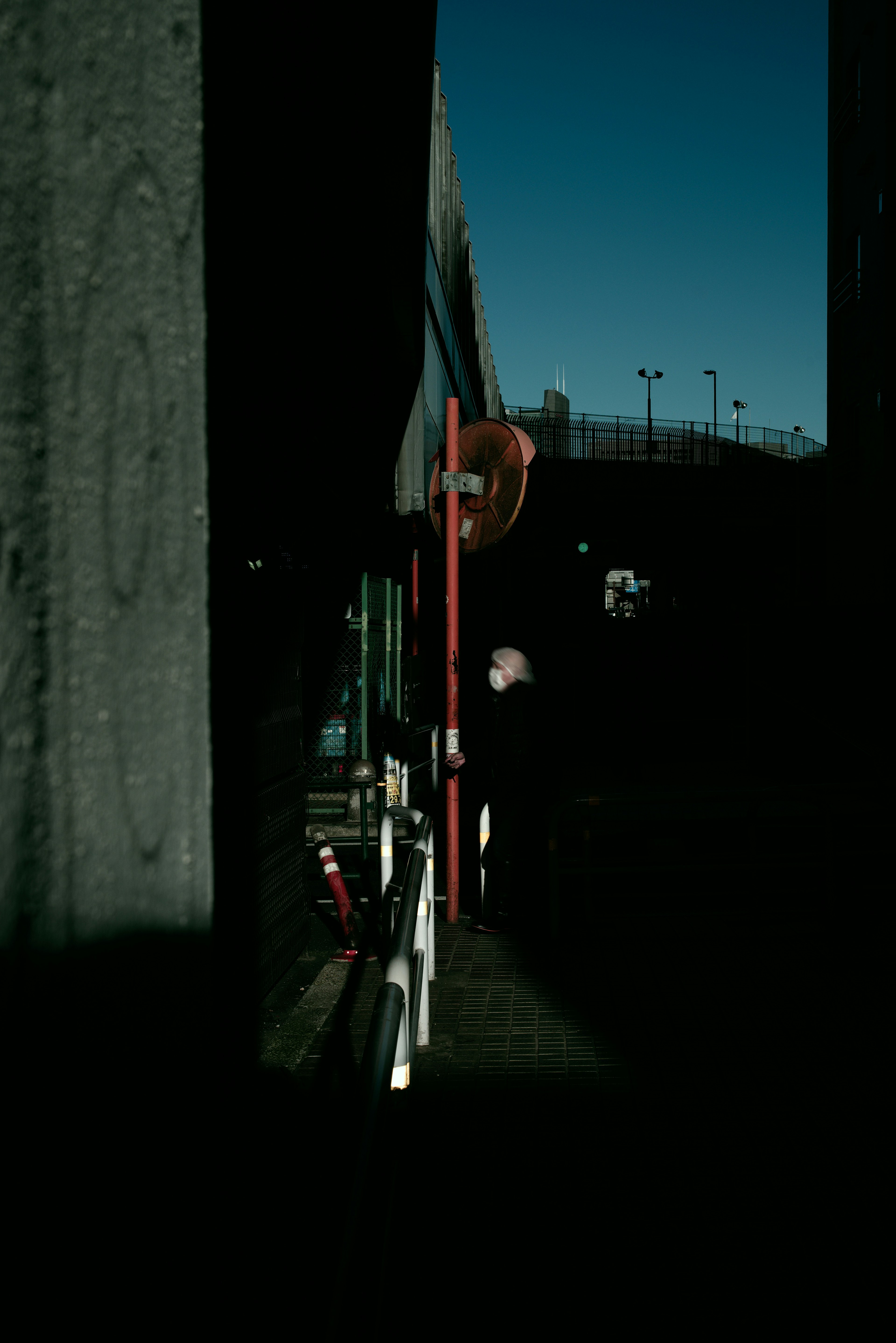 Silhouette d'une personne debout dans un coin de rue sombre avec un panneau rouge