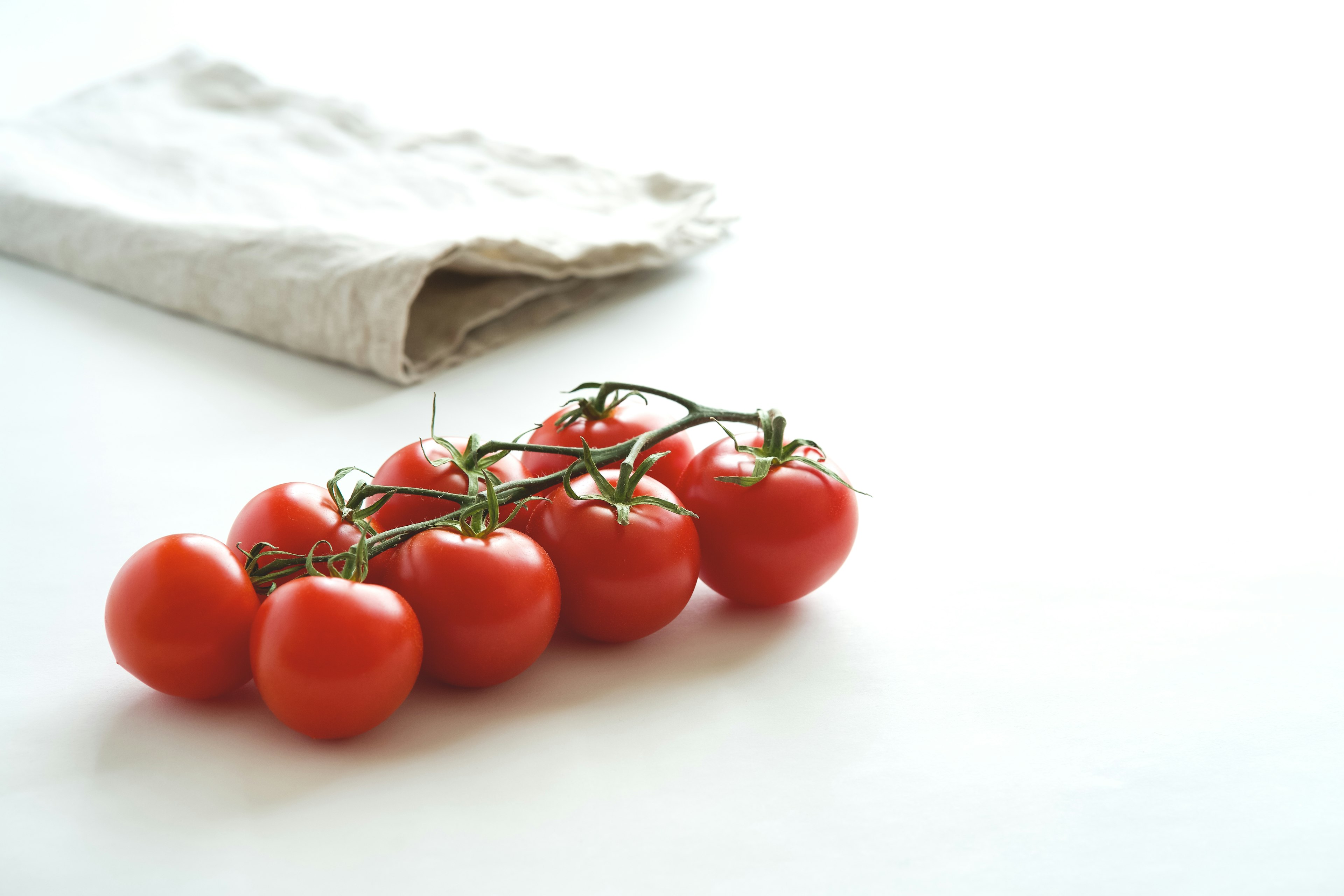 Un grappolo di pomodori freschi con un tovagliolo sullo sfondo