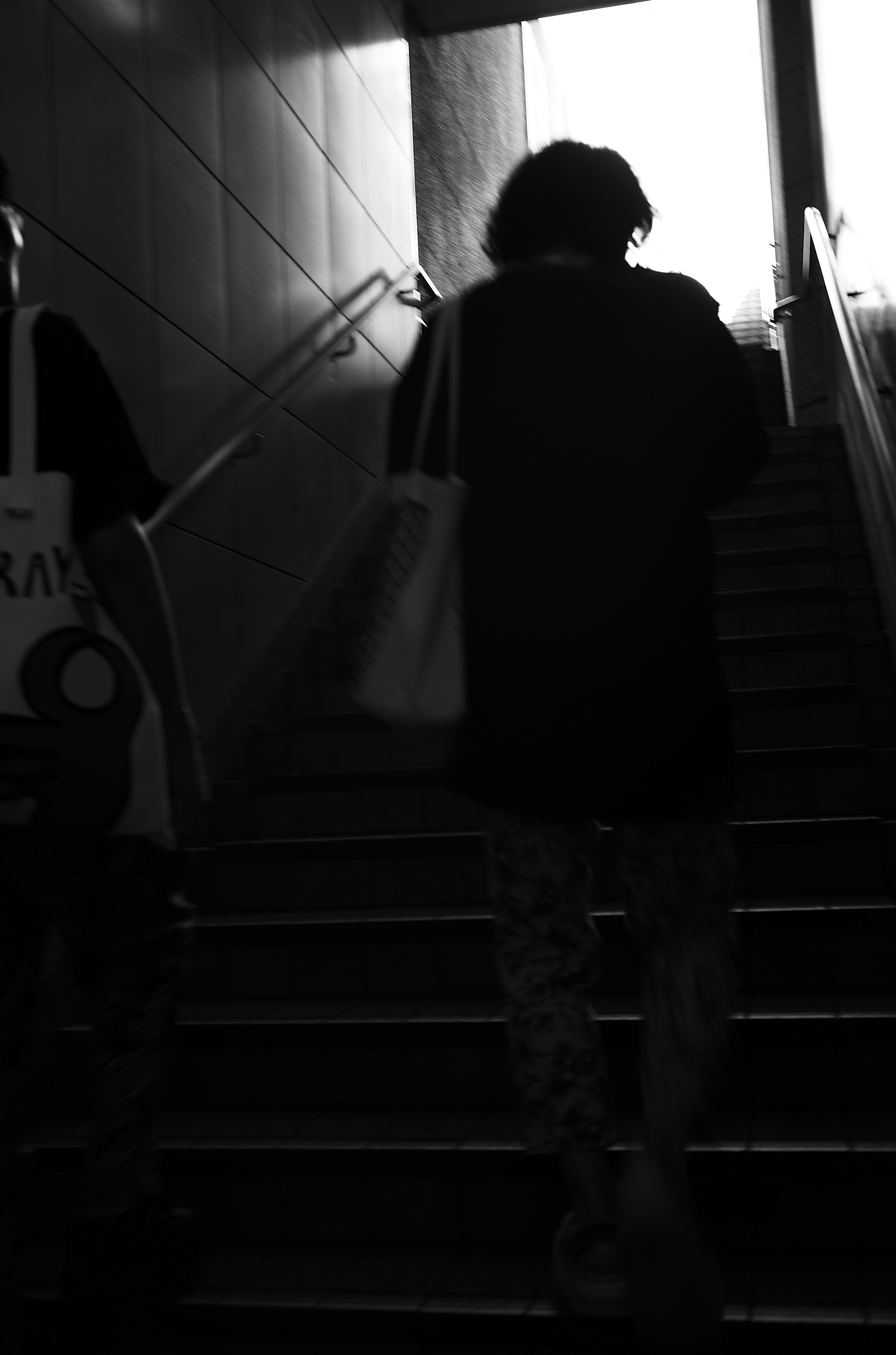 Silhouette d'une personne montant des escaliers avec une lumière de sortie brillante