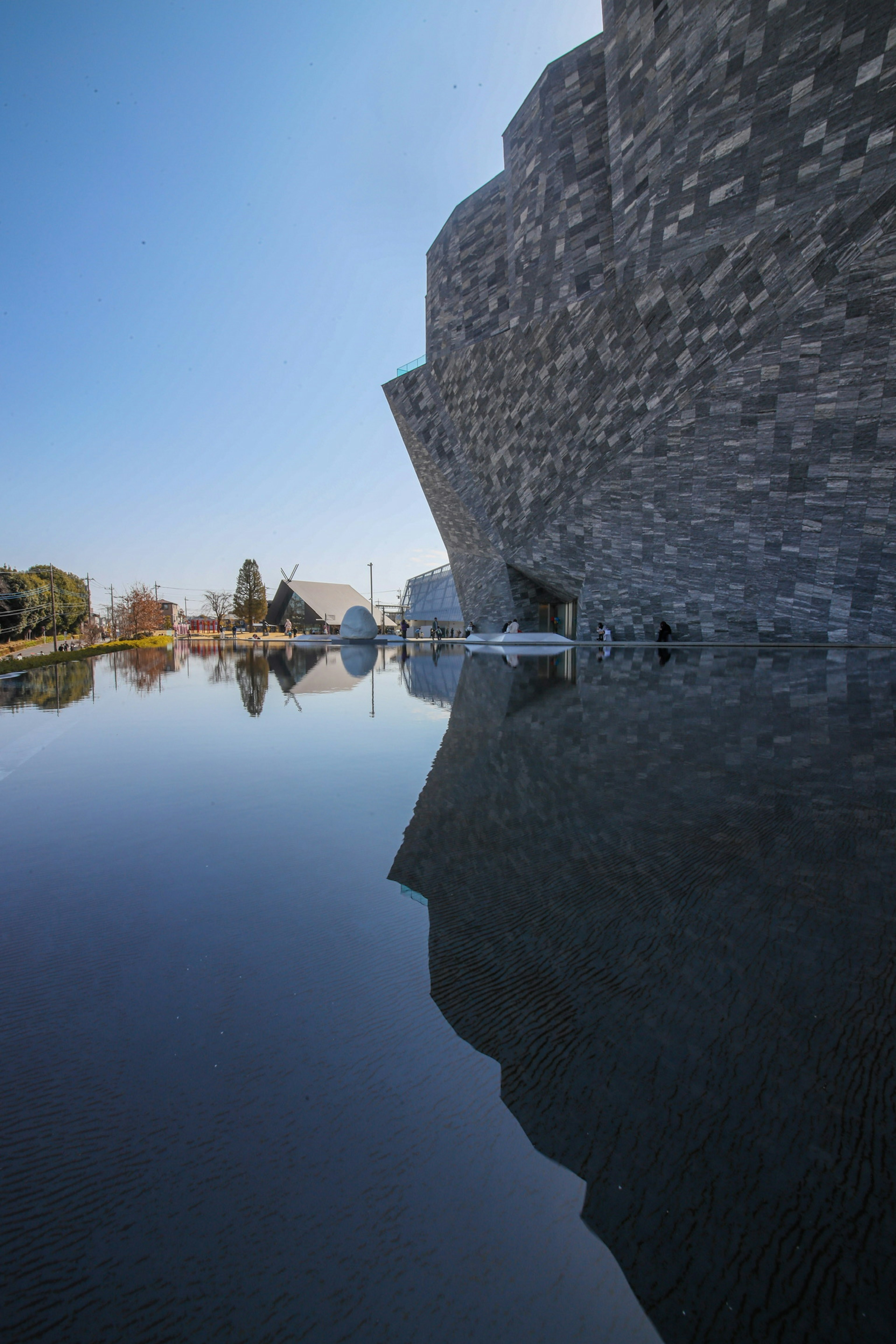 Modern stone building reflected on water with clear blue sky