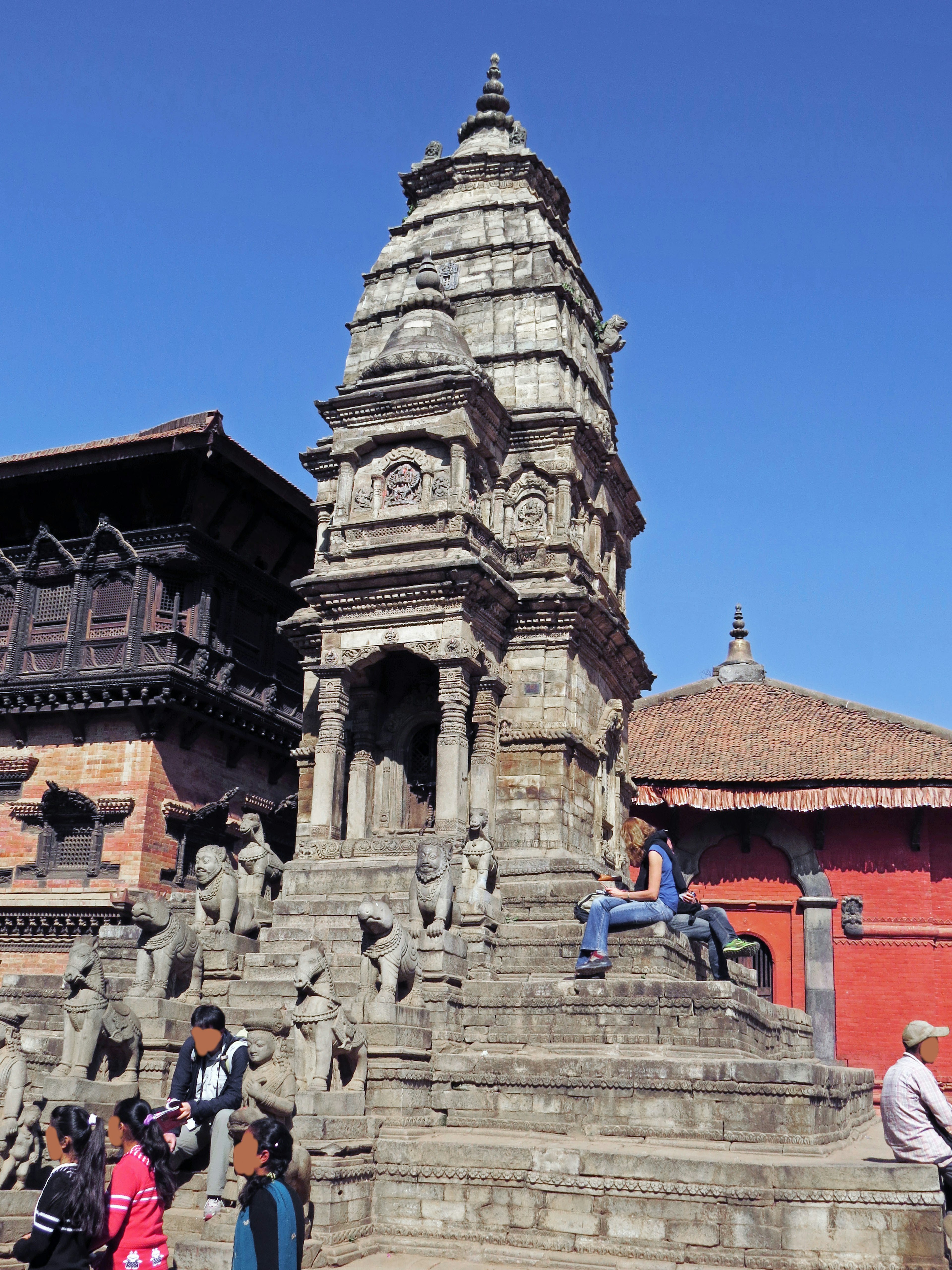 Traditional temple tower in Nepal under a blue sky surrounded by tourists