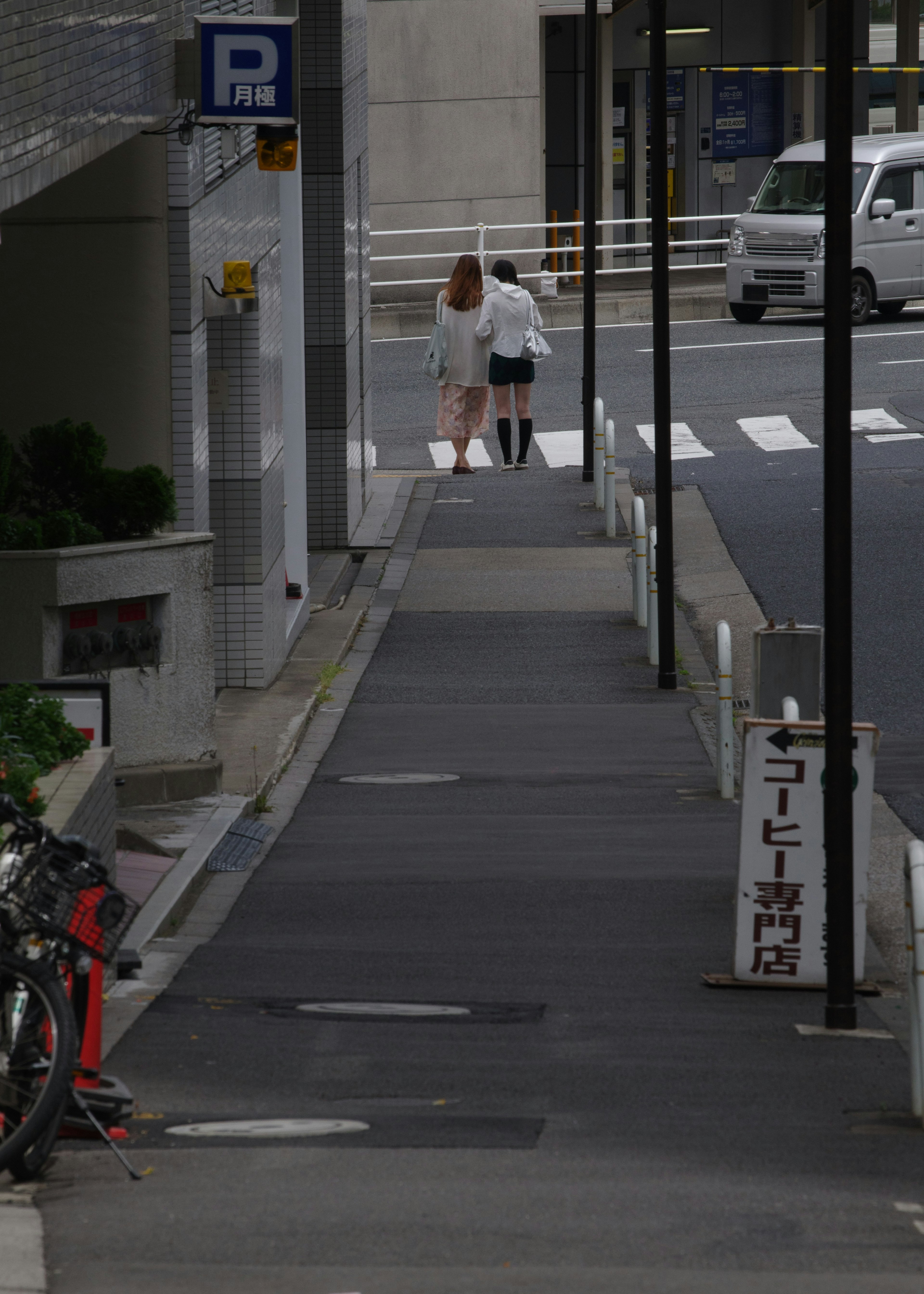 歩道を歩く二人の人物が見える街の風景