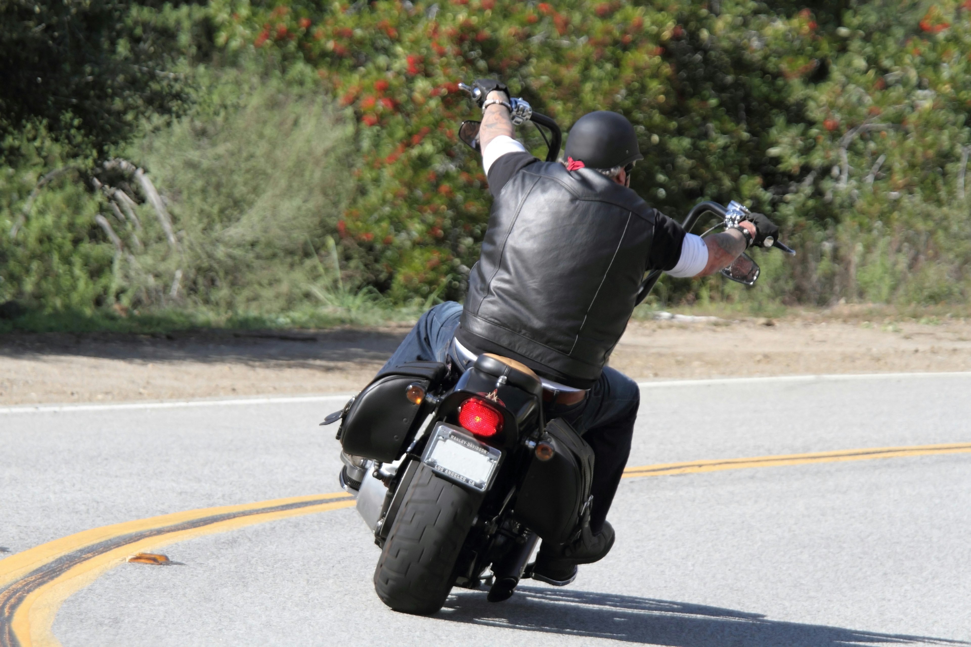 A man riding a motorcycle around a curve on a scenic road