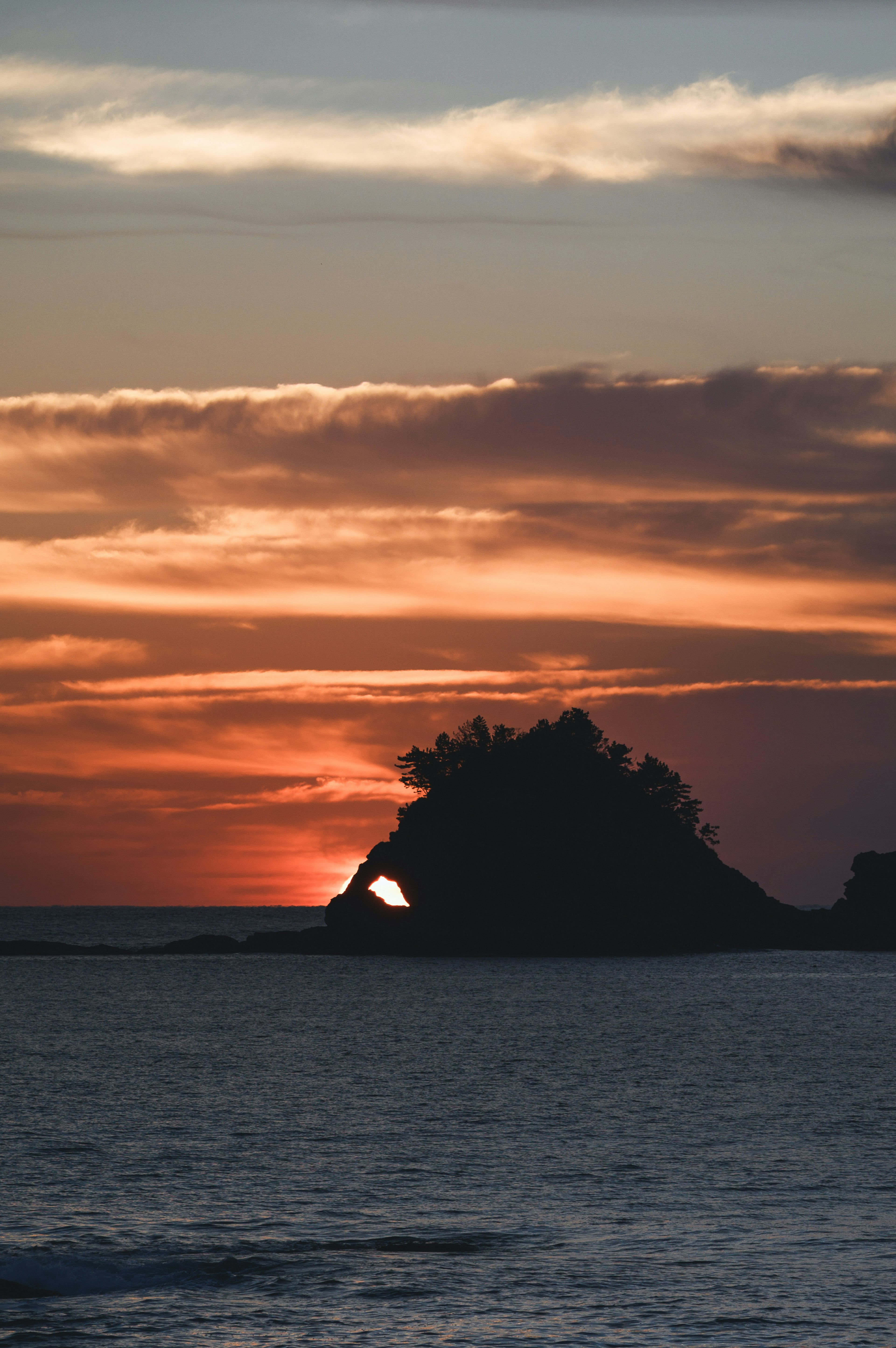 夕日が沈む海に浮かぶ島のシルエット