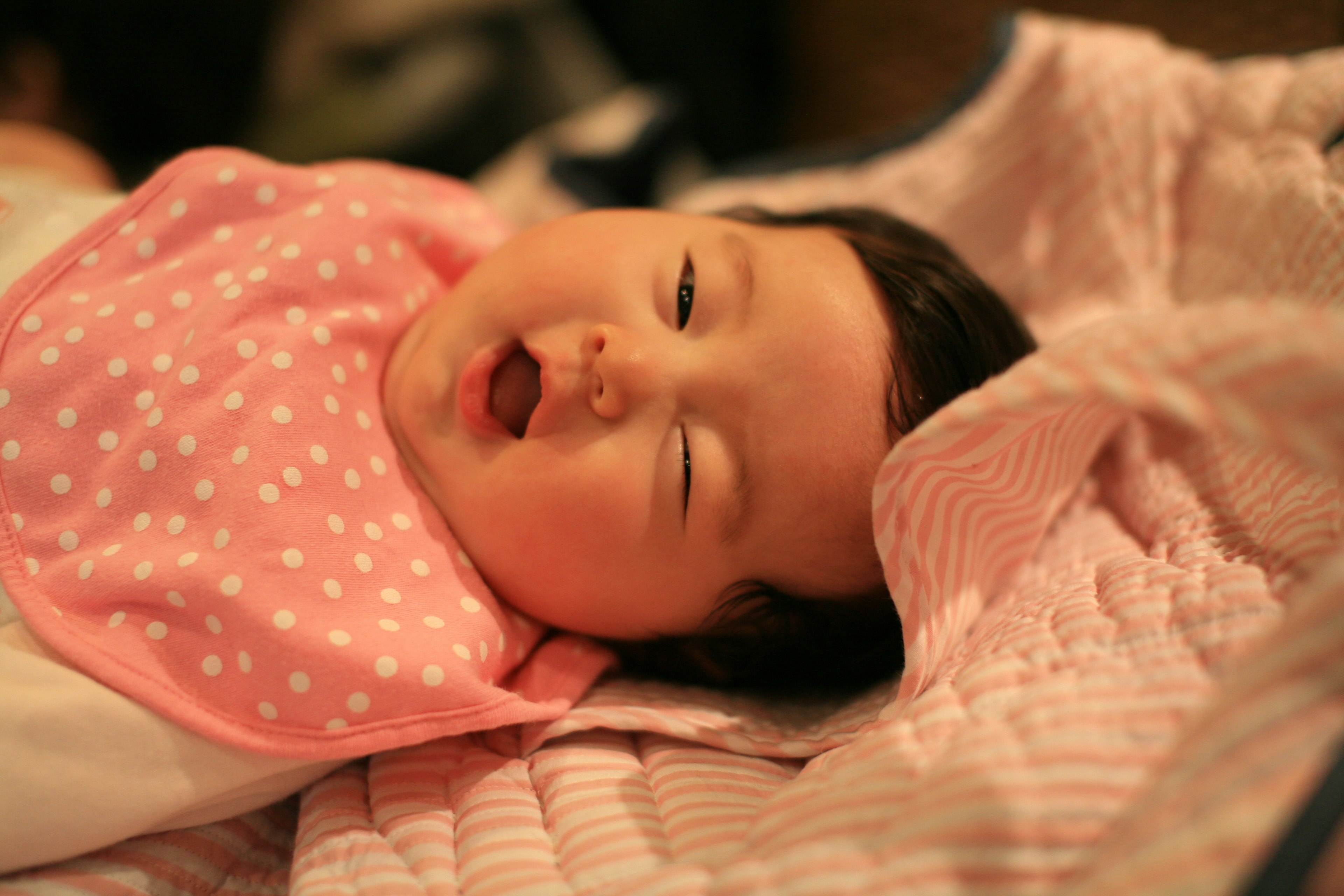 Baby mit einem rosa Lätzchen mit weißen Punkten