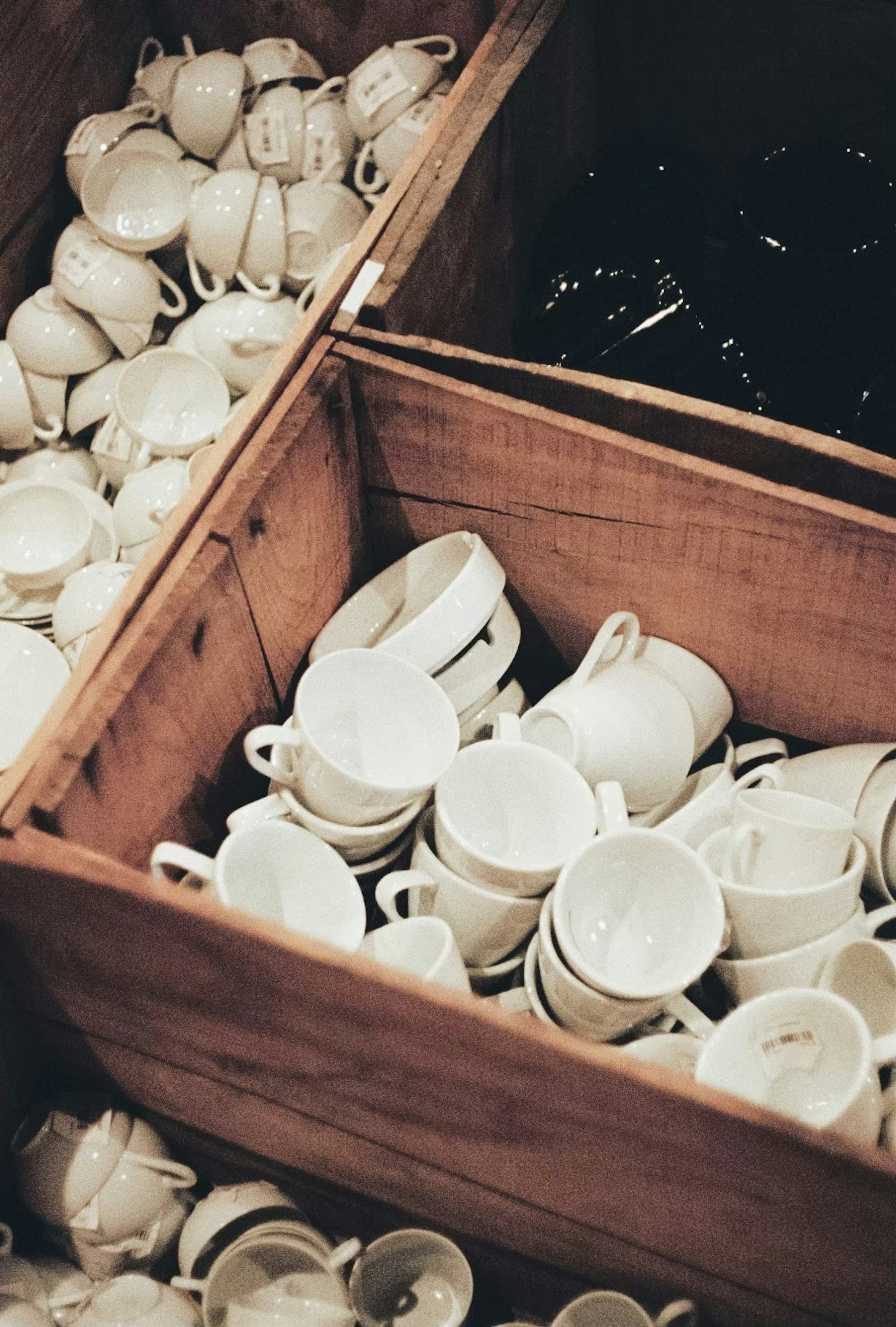 Collection of white and black cups stacked in wooden boxes